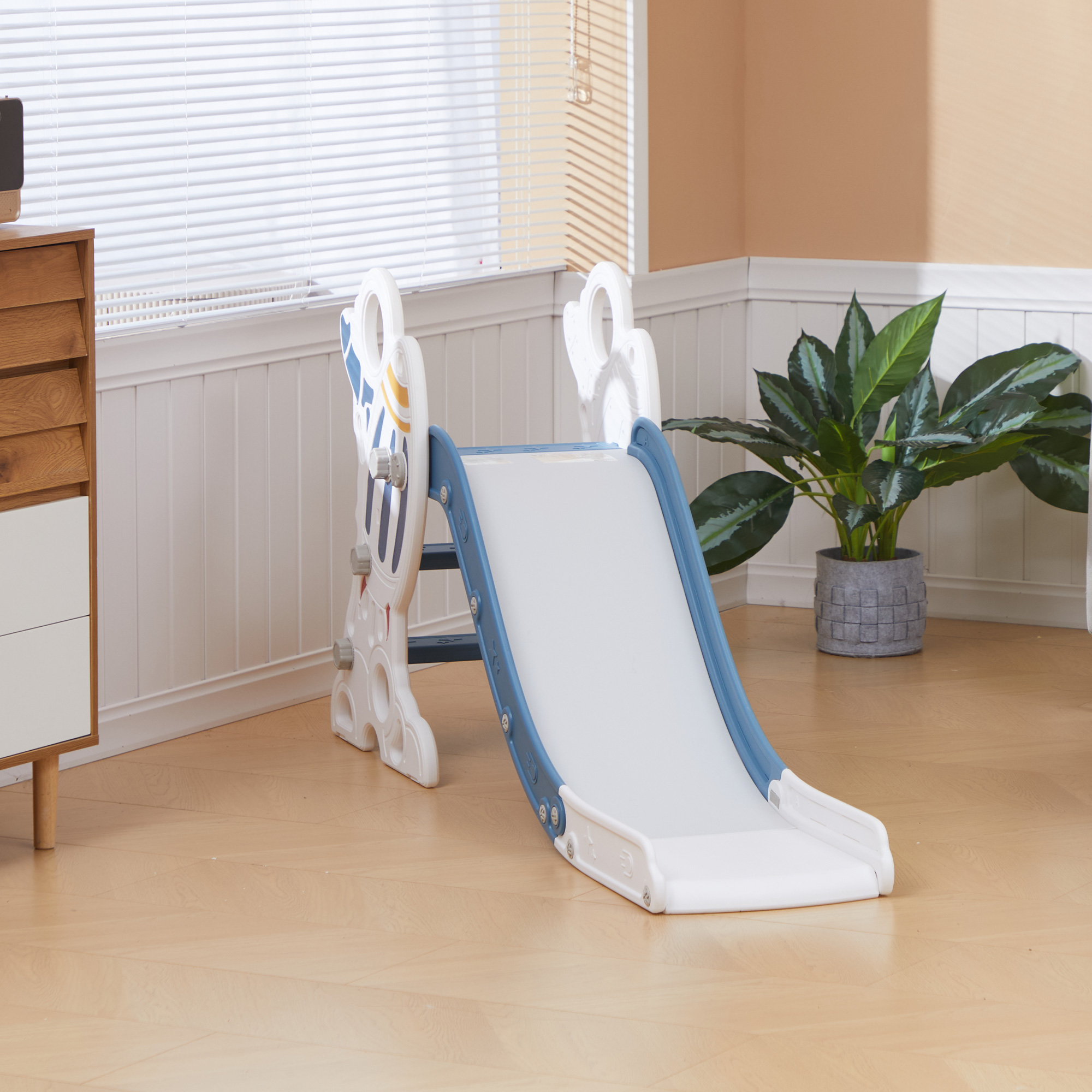 Uno scivolo di plastica blu e bianco per bambini è su un pavimento in legno.