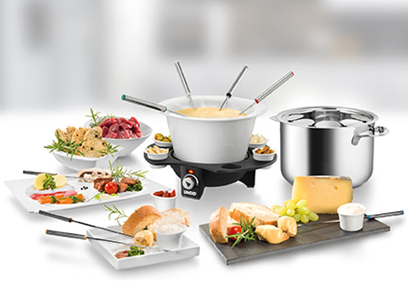 Fondue-Set mit Käse, Brot, Fleisch und Gemüse auf weißen Tellern.