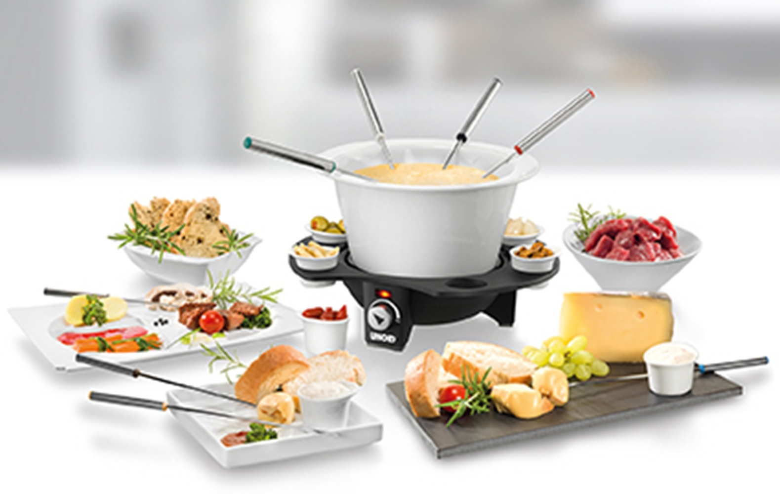 Zestaw do fondue z serem, chlebem, mięsem i sosami.