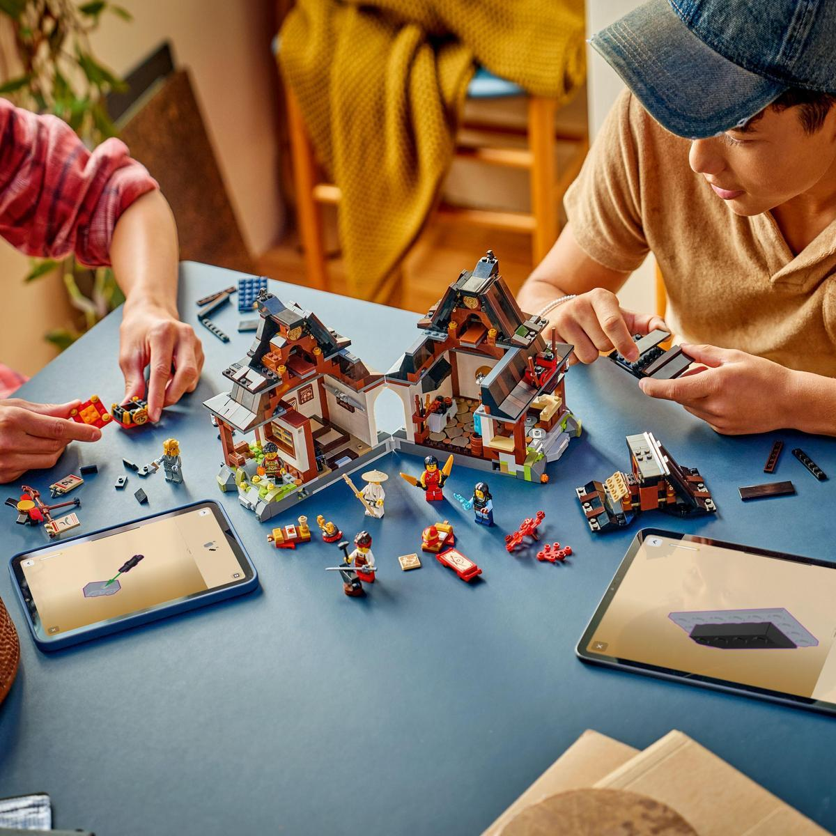 İki çocuk, talimatları gösteren figürler ve tabletlerle bir Lego tapınağı inşa ediyor.