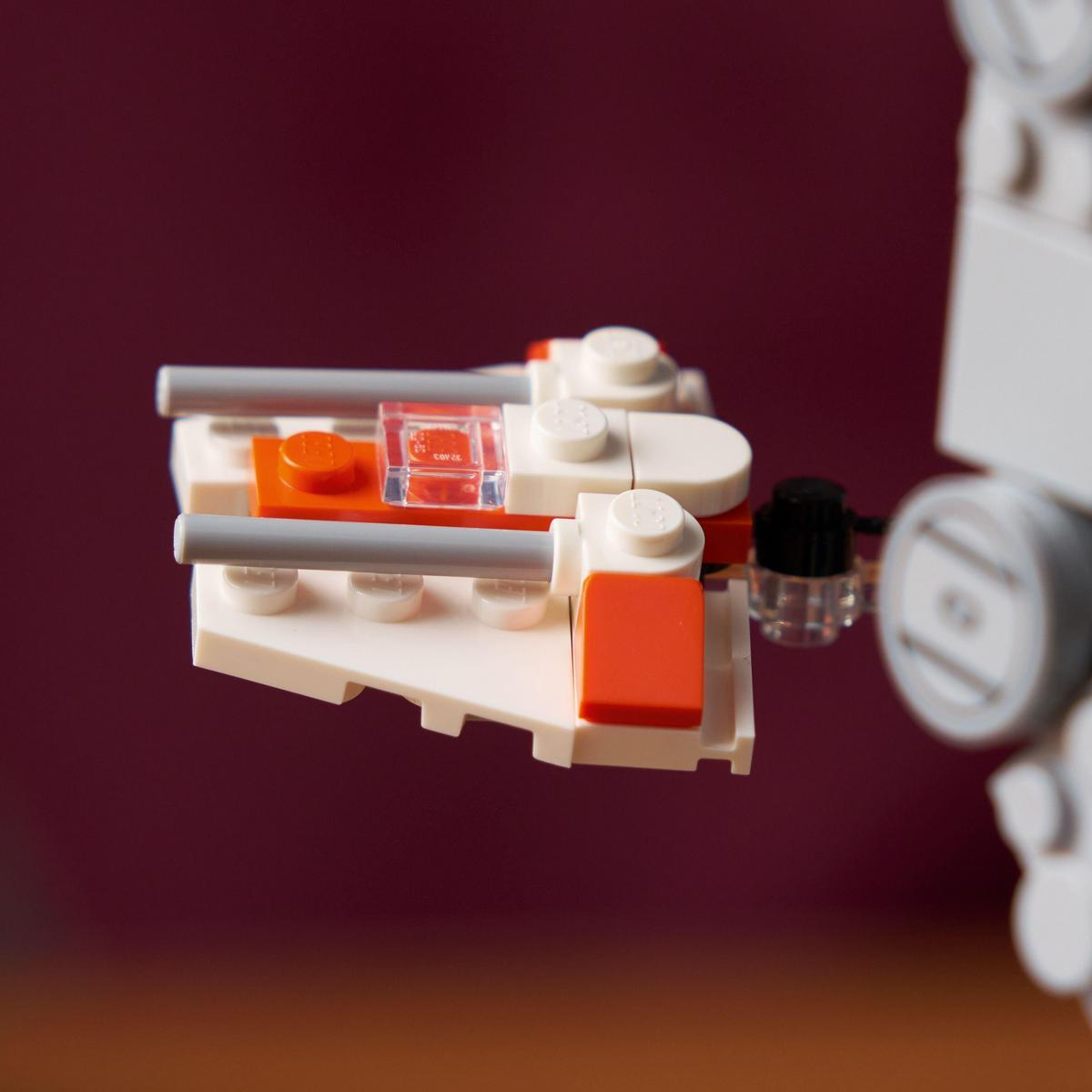 Koyu kırmızı arka plana karşı gri toplara sahip beyaz ve turuncu Lego uzay gemisi.