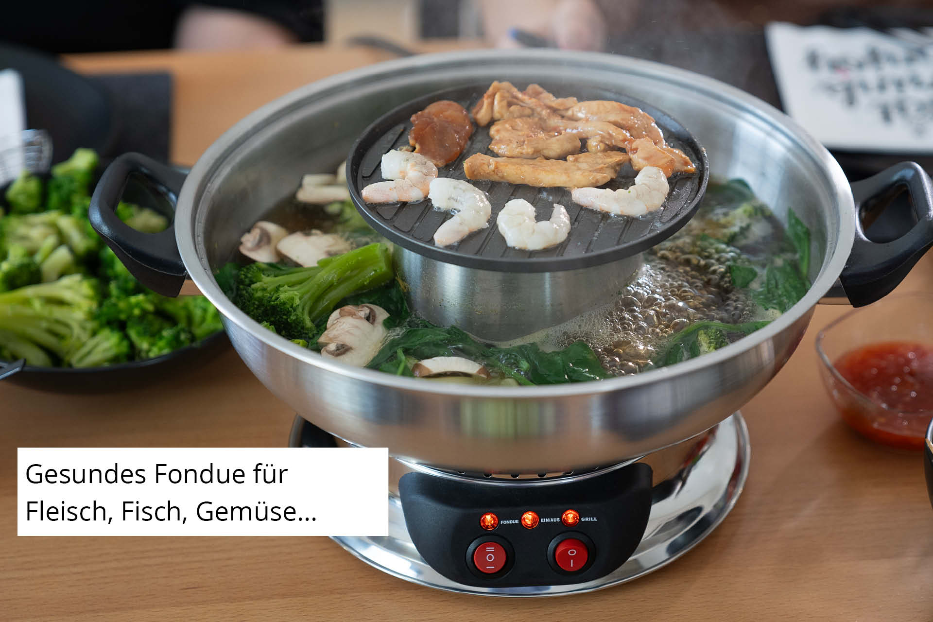 Una pentola da fonduta cuoce carne, gamberi e verdure.