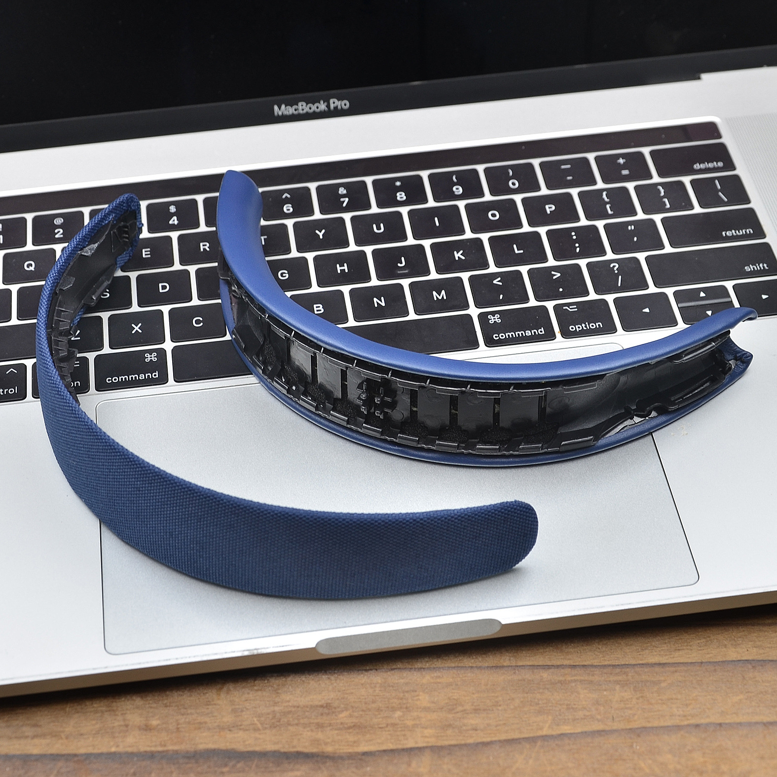 Niebieska opaska słuchawek leży na klawiaturze MacBook Pro.