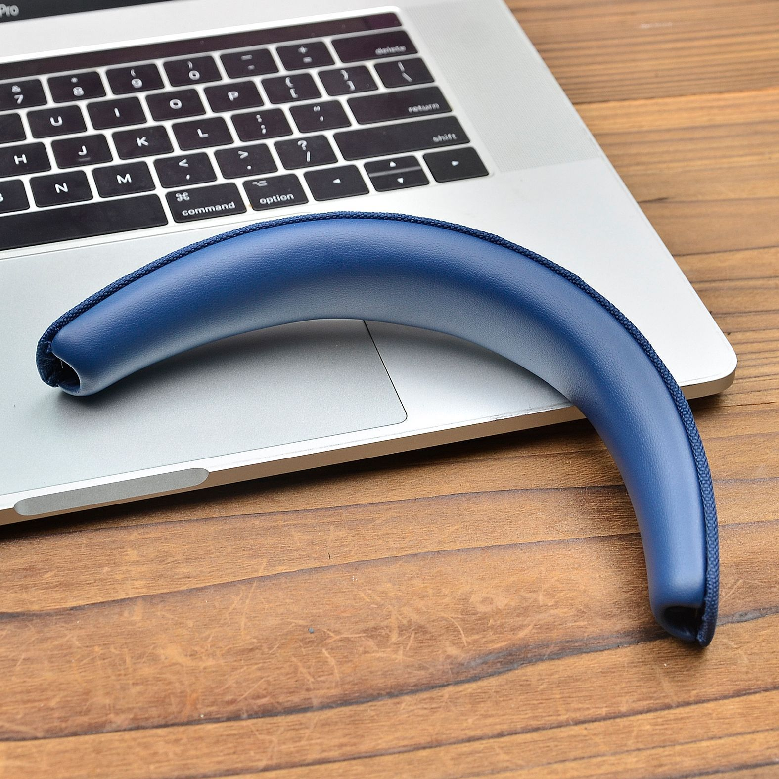 Niebieska poduszka słuchawek leży na klawiaturze laptopa.