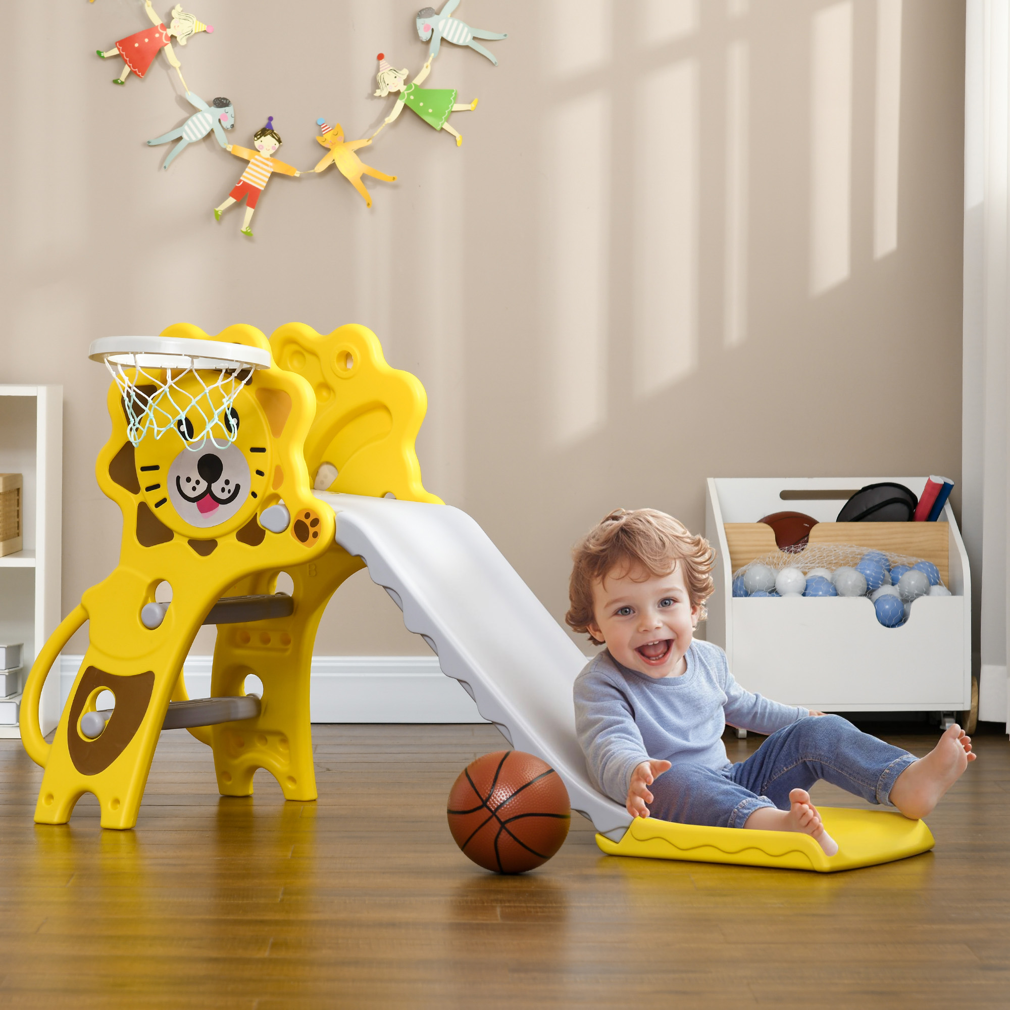 Un bambino scivola su uno scivolo giallo, un pallone da basket è nelle vicinanze.