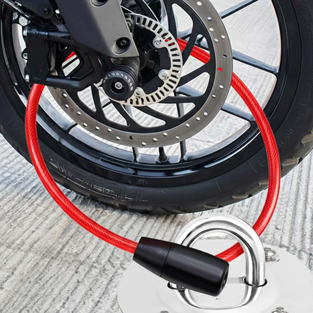 Rotes Kabelschloss sichert Motorradrad an Metallanker auf Betonfläche.