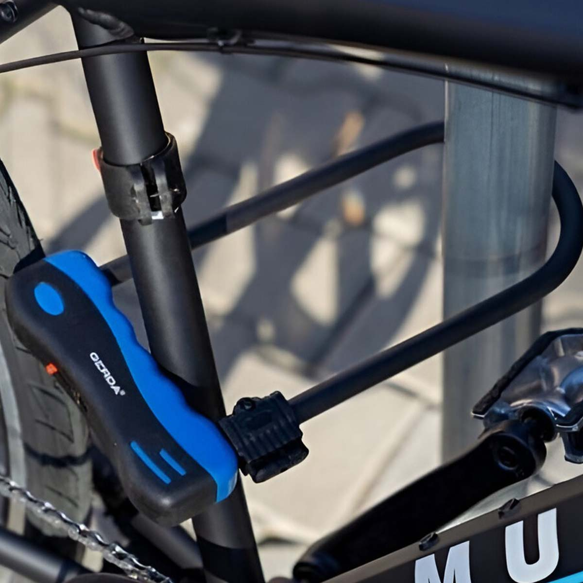 Ein schwarz-blaues Fahrradschloss ist am Rahmen eines schwarzen Fahrrads befestigt.