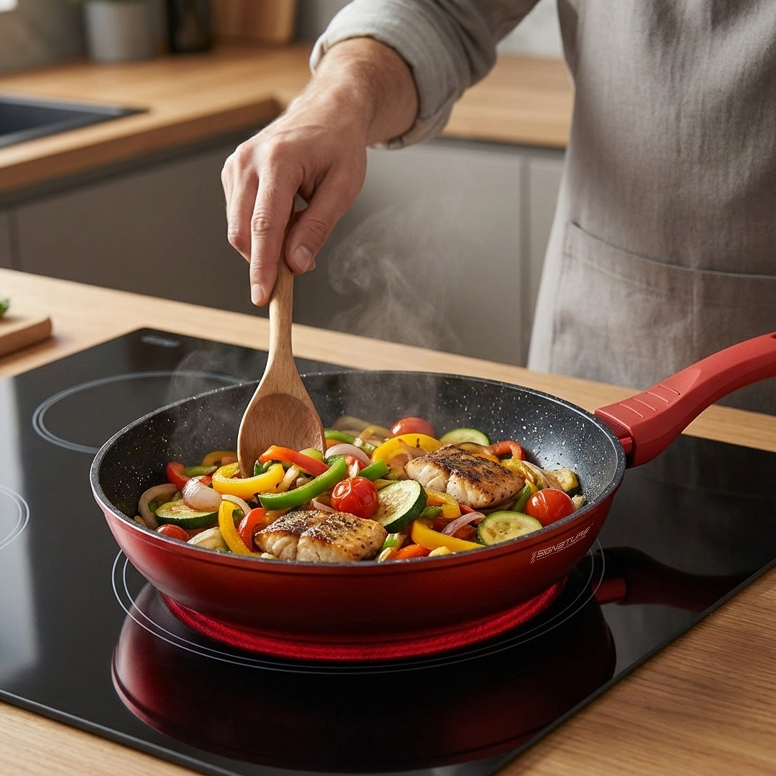 Personne cuisinant du poisson et des légumes colorés dans une poêle rouge sur une plaque.