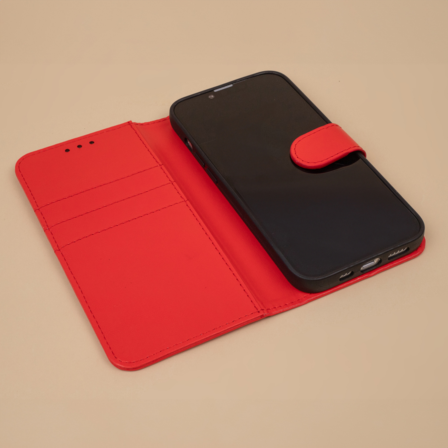 Eine rote offene Wallet-Handyhülle mit einem schwarzen Telefon darin, auf beigem Hintergrund.