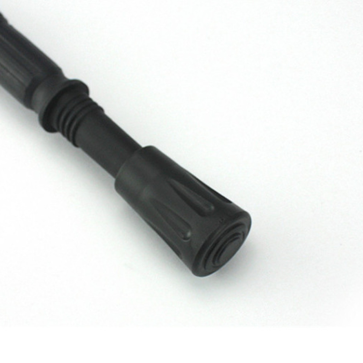 Zbliżenie czarnego uchwytu kijka trekkingowego z rowkami na białym tle.