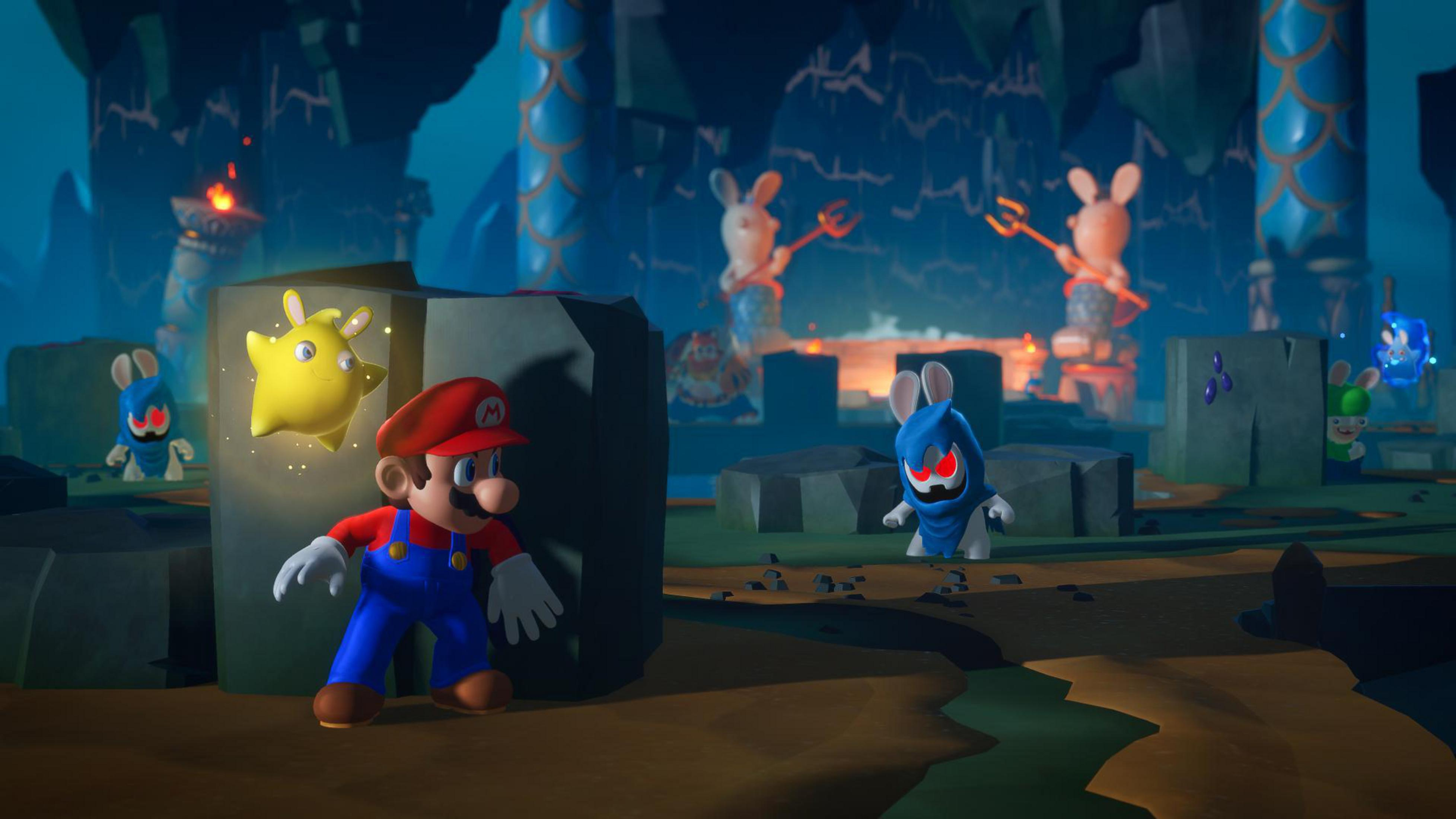 Mario, une étoile jaune et des Rabbids bleus dans un environnement sombre, de type grotte.