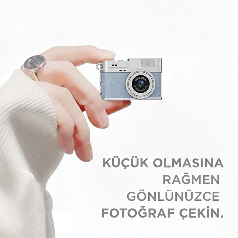 Bir el küçük, açık mavi ve gümüş dijital kamera tutuyor. Bilekte saat var.