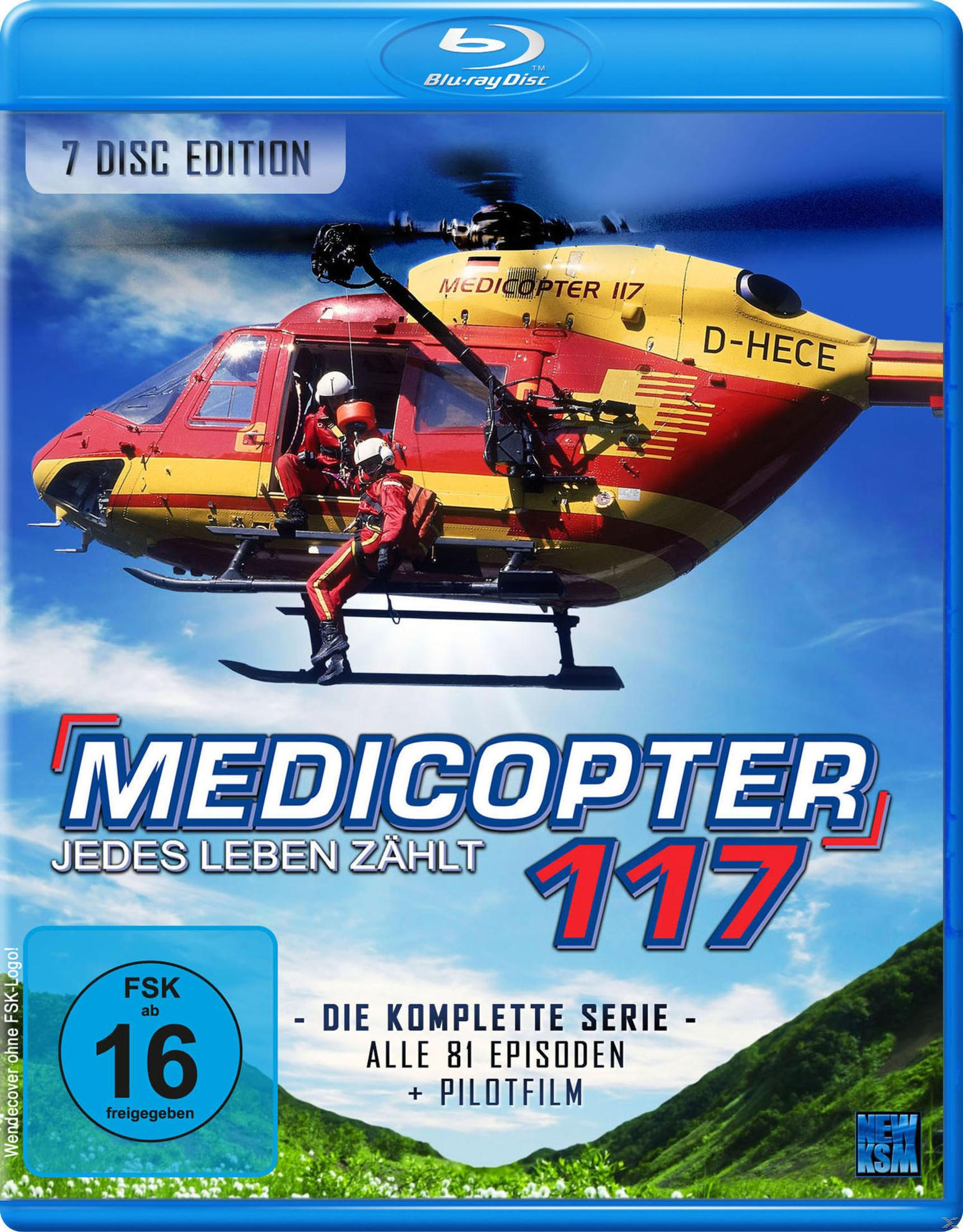 Un elicottero rosso e giallo Medicopter 117 vola in cielo blu, con due membri dell'equipaggio visibili.