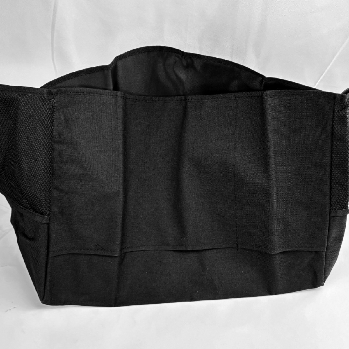 Bolso de tela negro con laterales de malla y múltiples compartimentos.