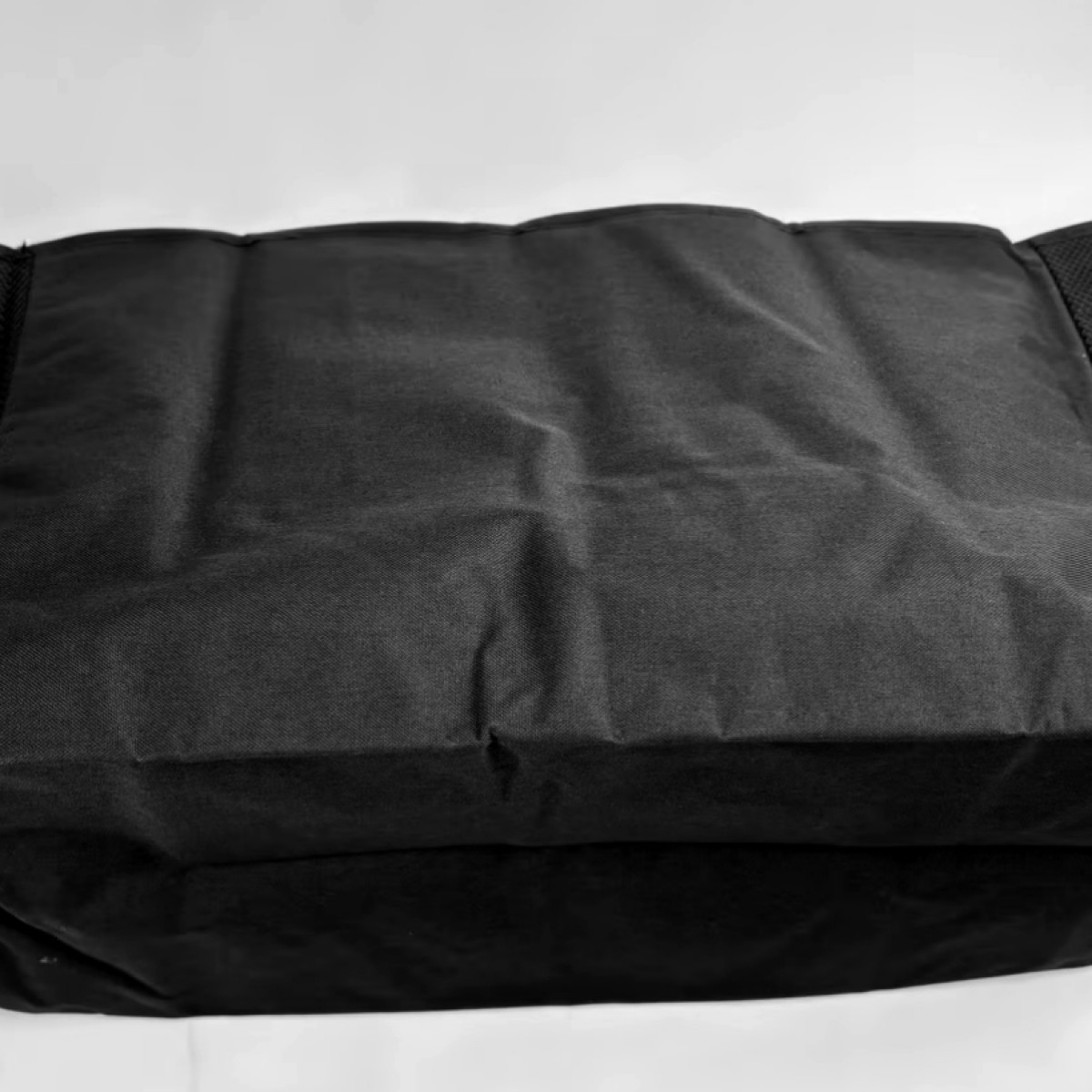 Una mochila negra con textura de tela y pliegues, sobre fondo blanco.