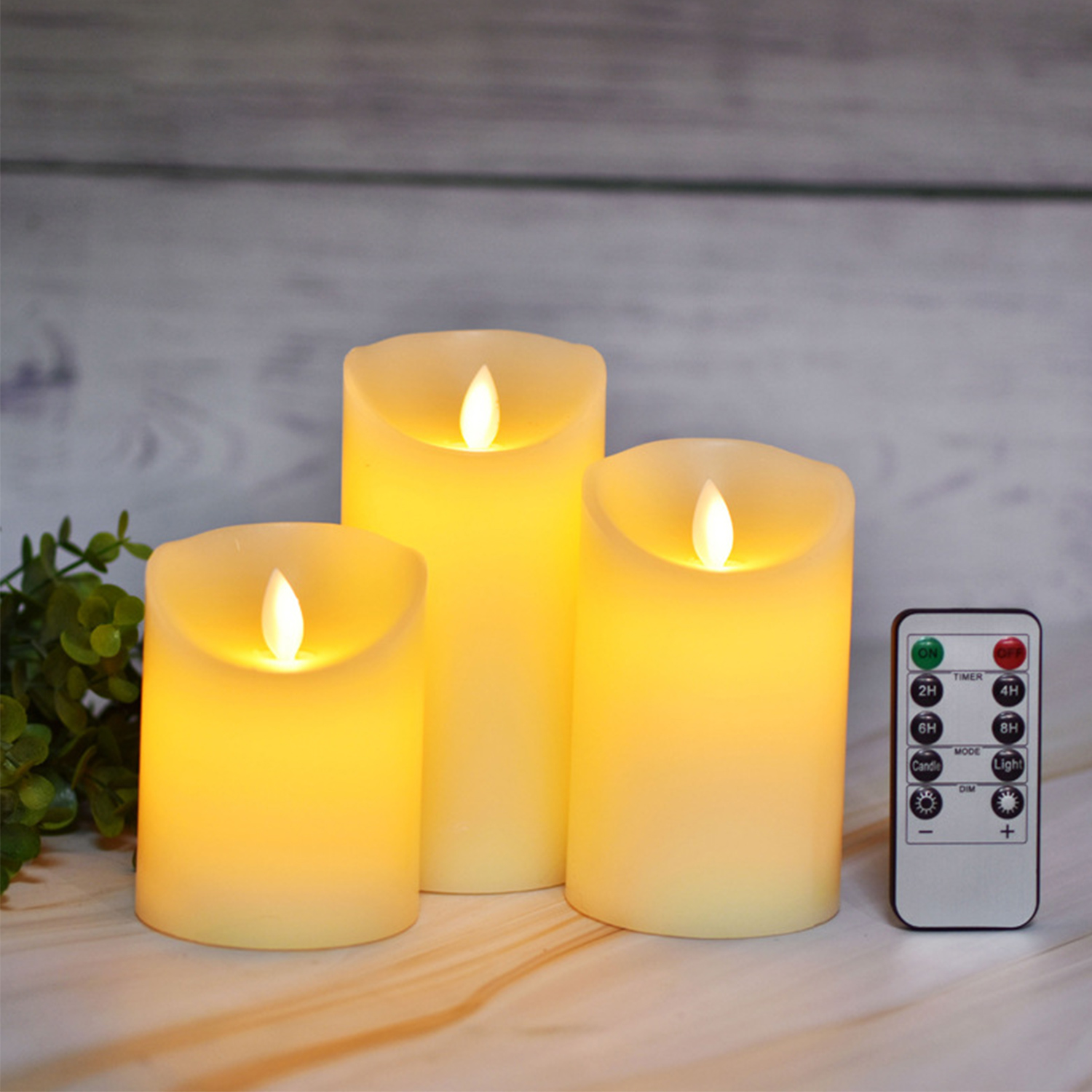 Trzy świece LED o różnej wielkości świecą na żółto. Obok leży pilot.