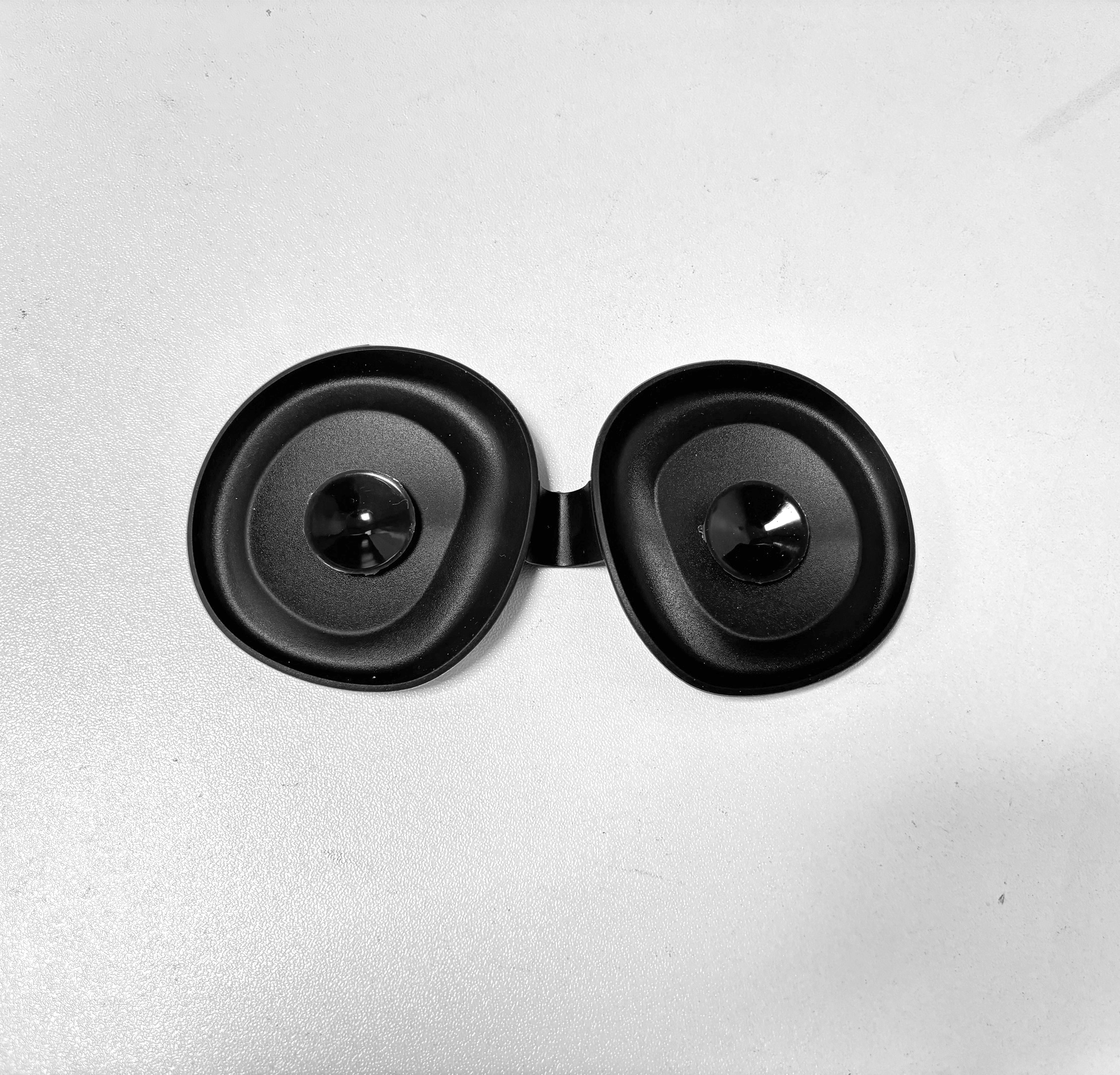 Dwa czarne, okrągłe słuchawki z błyszczącymi środkami na białym tle.