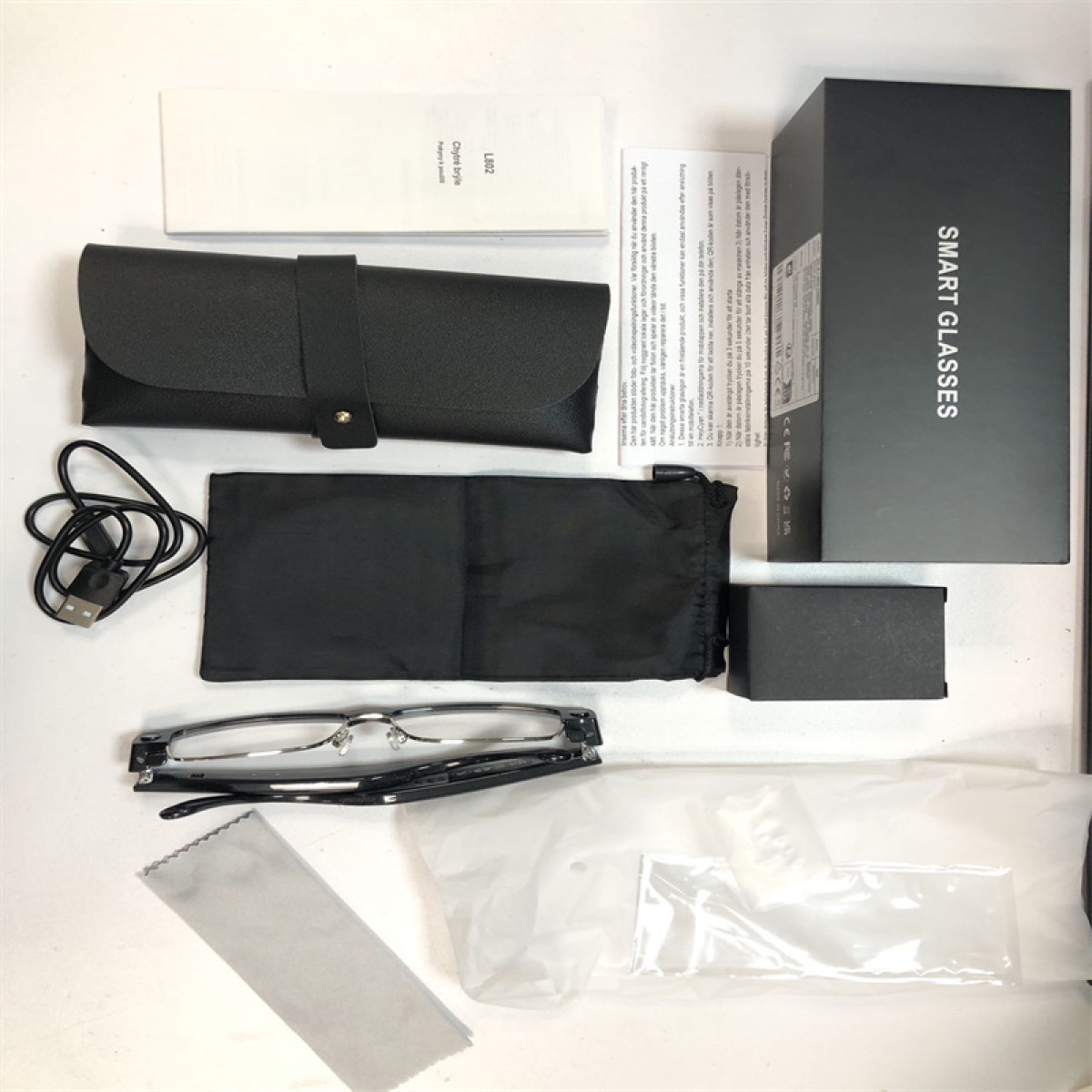 Zestaw czarnych okularów inteligentnych z akcesoriami, w tym etui i kabel ładujący.