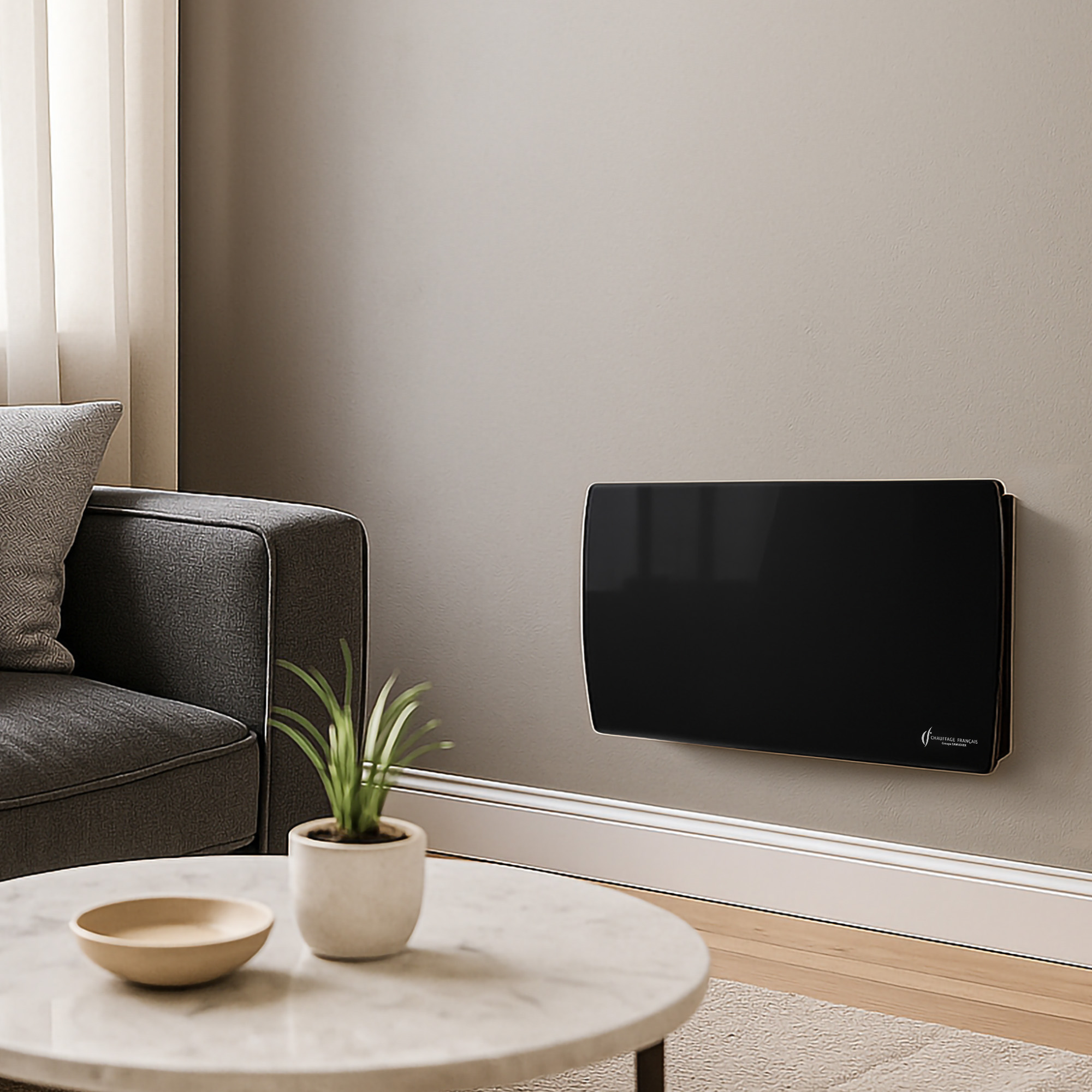 Ein schwarzer Elektroheizer an einer hellgrauen Wand über einer weißen Fußleiste. Ein Sofa und ein Couchtisch sind sichtbar.