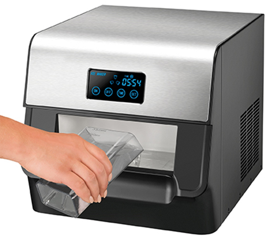 Dłoń wkłada przezroczysty pojemnik na lód do srebrno-czarnej kostkarki z cyfrowym wyświetlaczem.