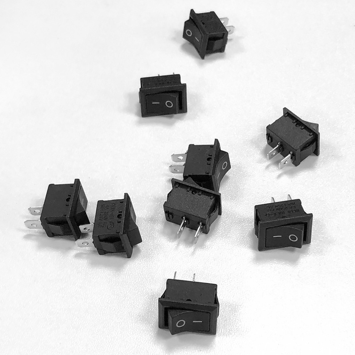 Kilka czarnych przełączników kołyskowych z białym kółkiem i linią na białej powierzchni.