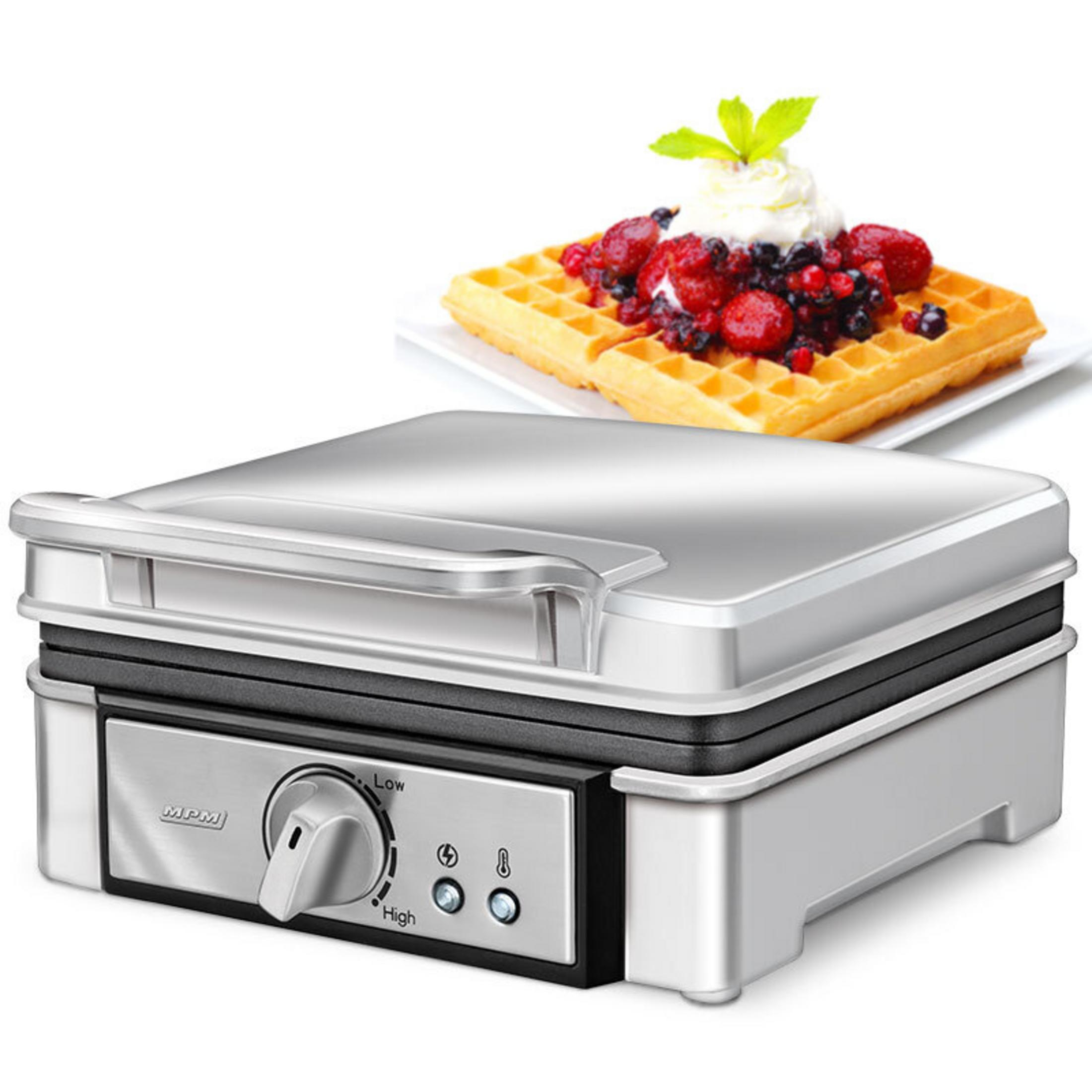 Ein silberner Waffelautomat mit einem fertigen Waffel mit Beeren und Sahne.