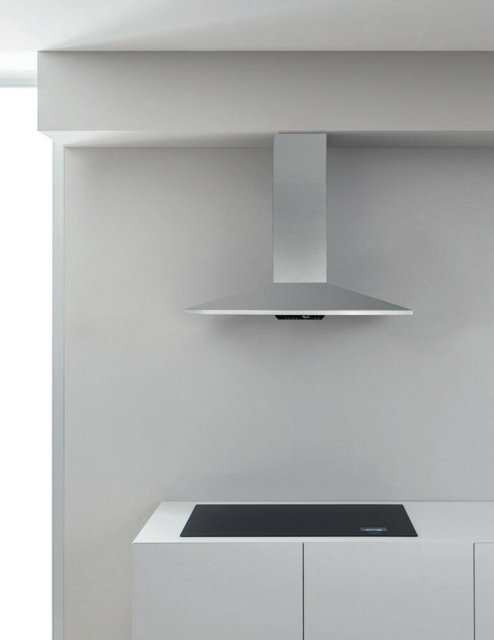 Una cocina moderna con campana extractora de acero inoxidable sobre una vitrocerámica de inducción negra.