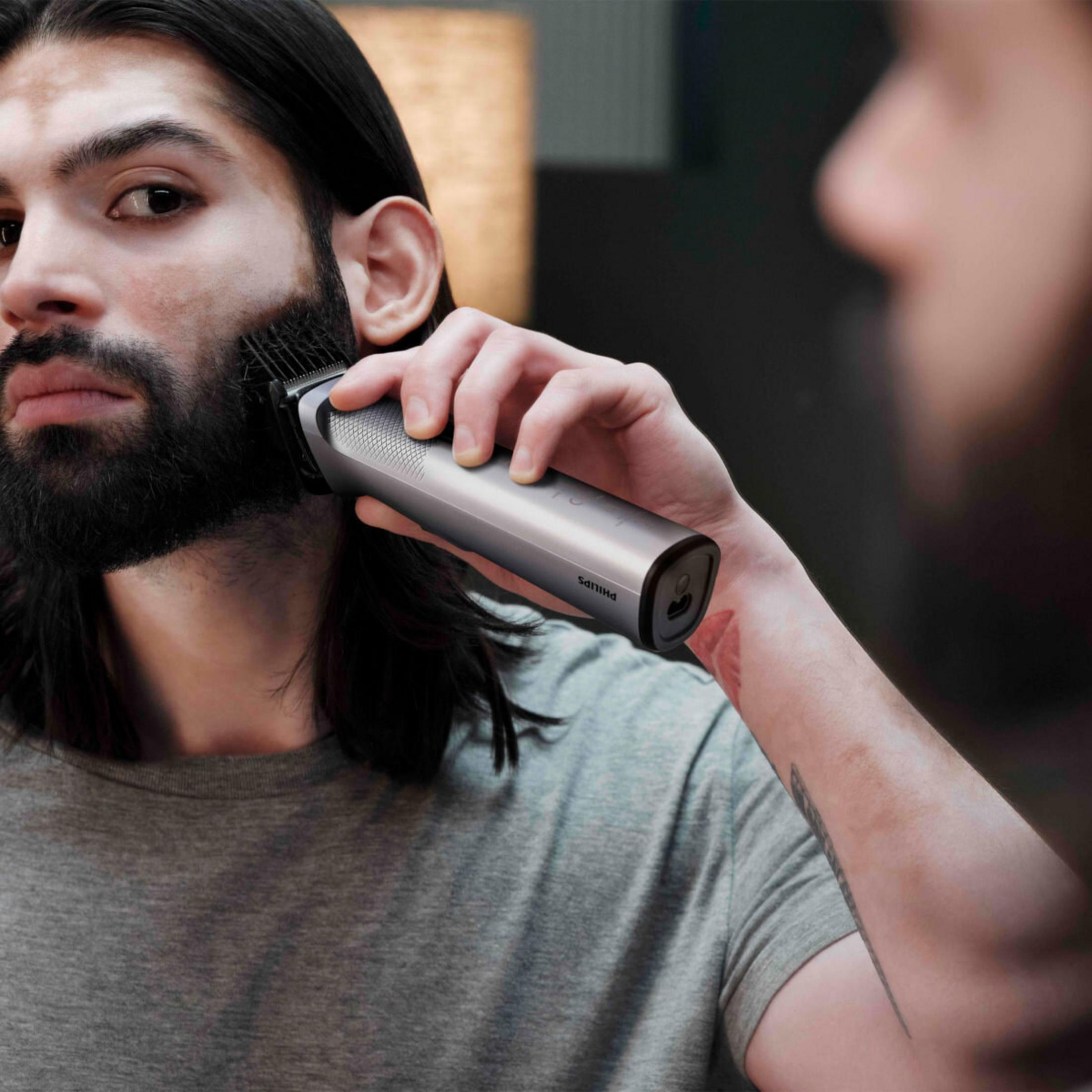 Uomo con vitiligine si taglia la barba con un rifinitore Philips argentato.