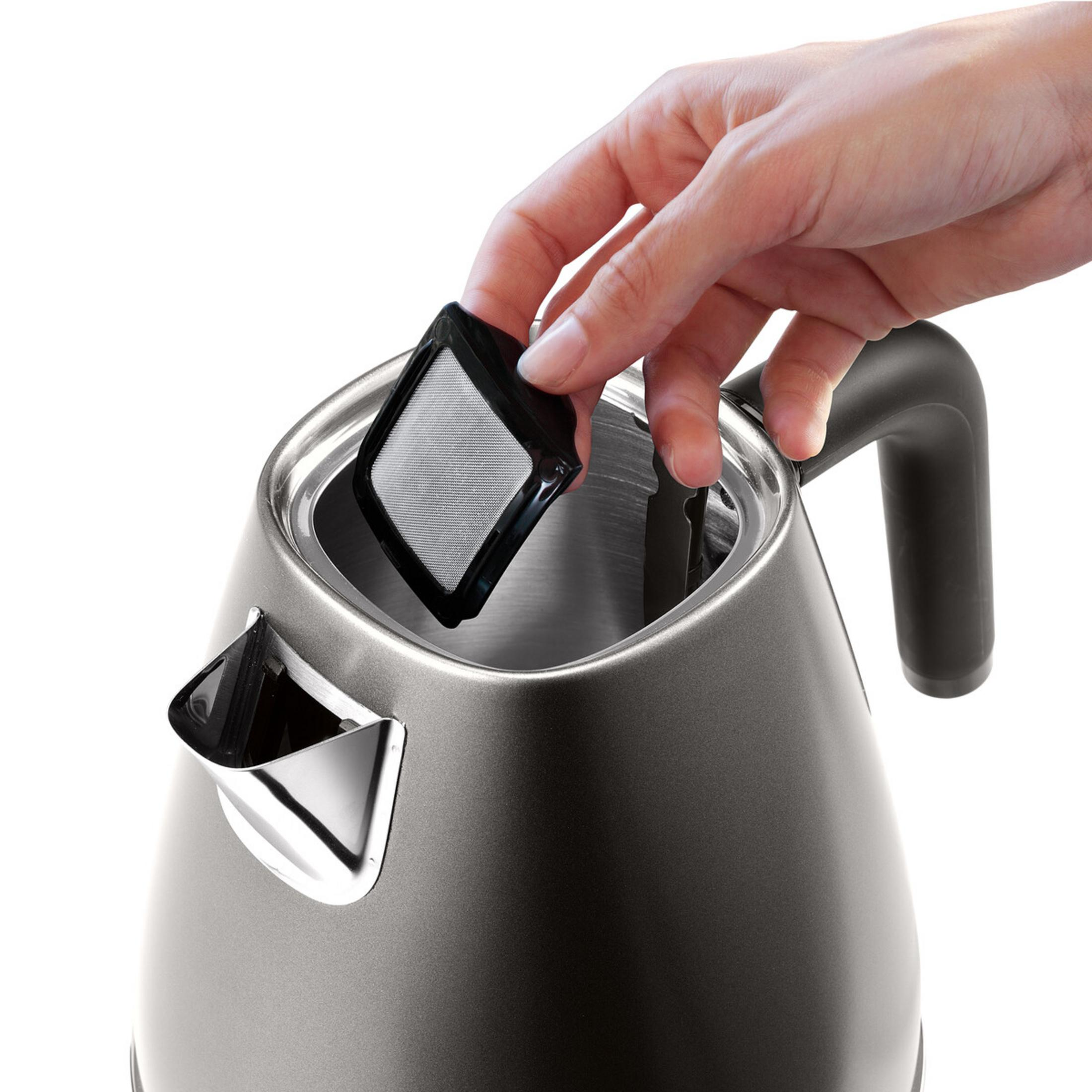 Eine Hand setzt einen schwarzen Teefilter in einen grauen Wasserkocher ein.