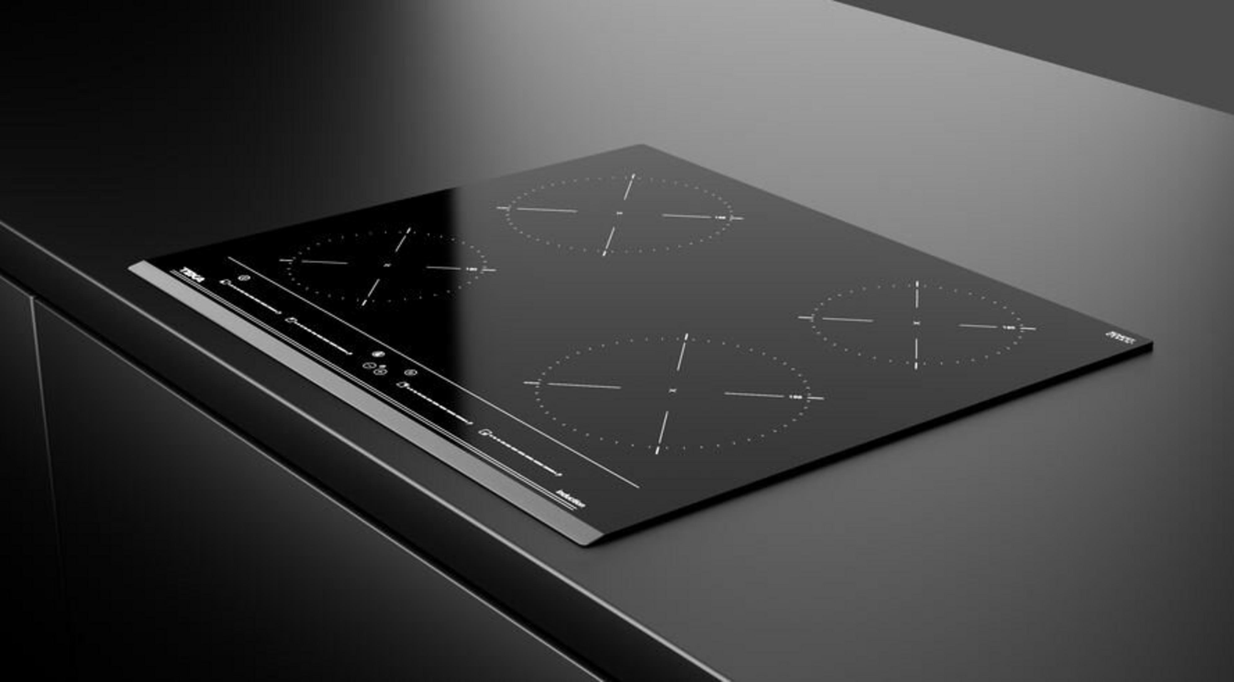 Una placa de inducción negra con cuatro zonas de cocción en una encimera oscura.