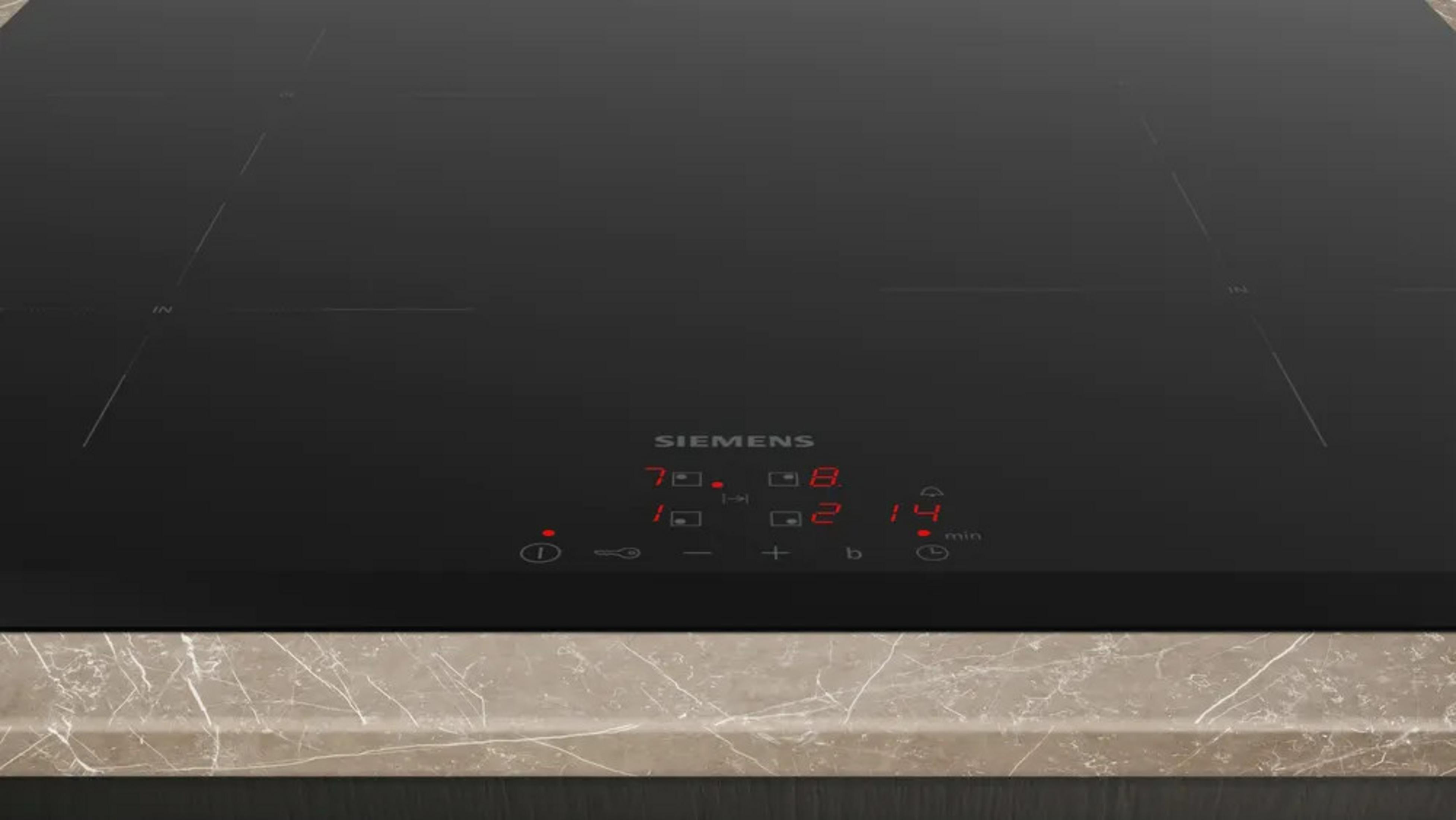 Een zwart inductiefornuis met digitale displays en een marmeren aanrechtblad.