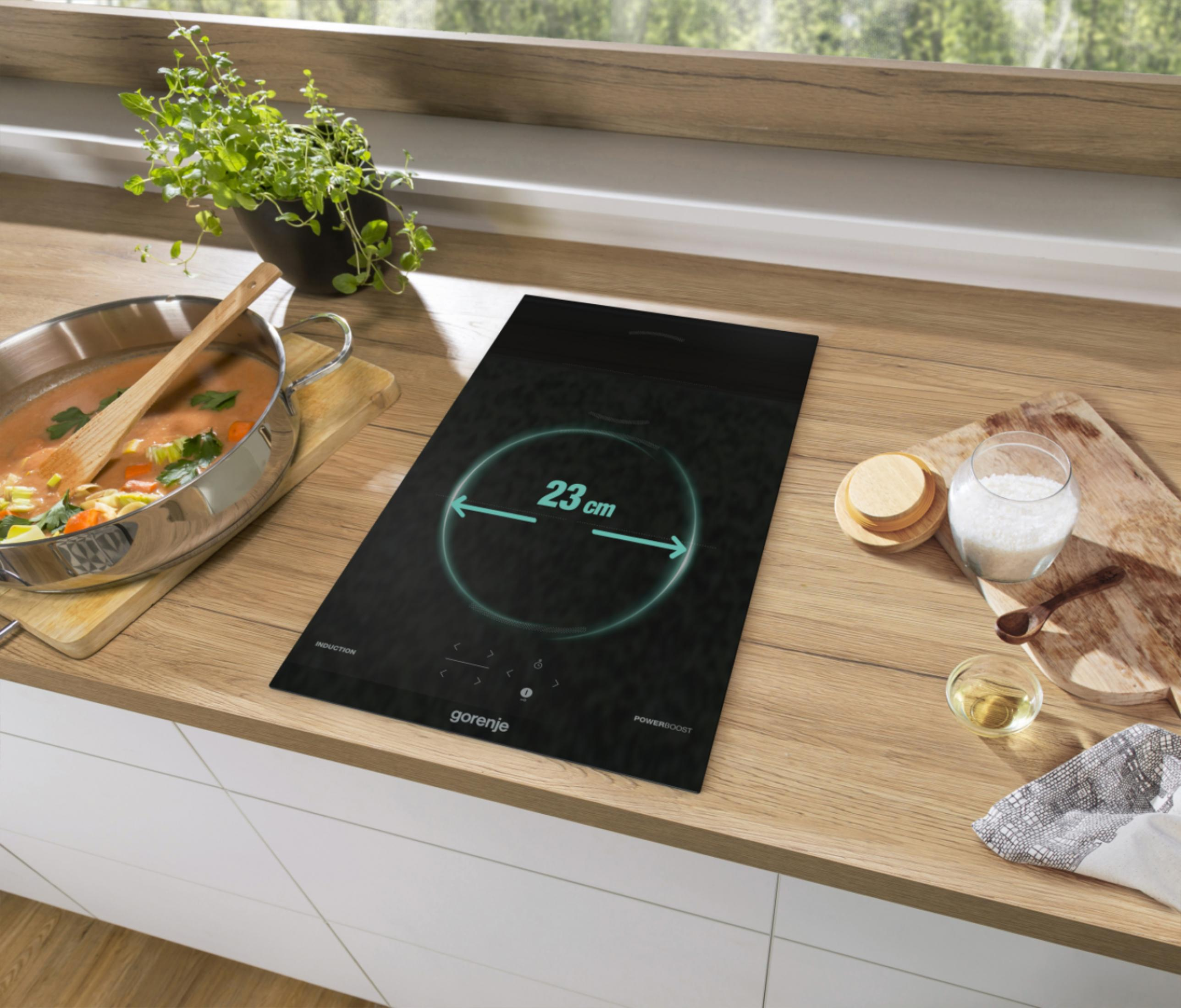 Ein Gorenje Induktionskochfeld zeigt 23cm an. Daneben steht ein Suppentopf.