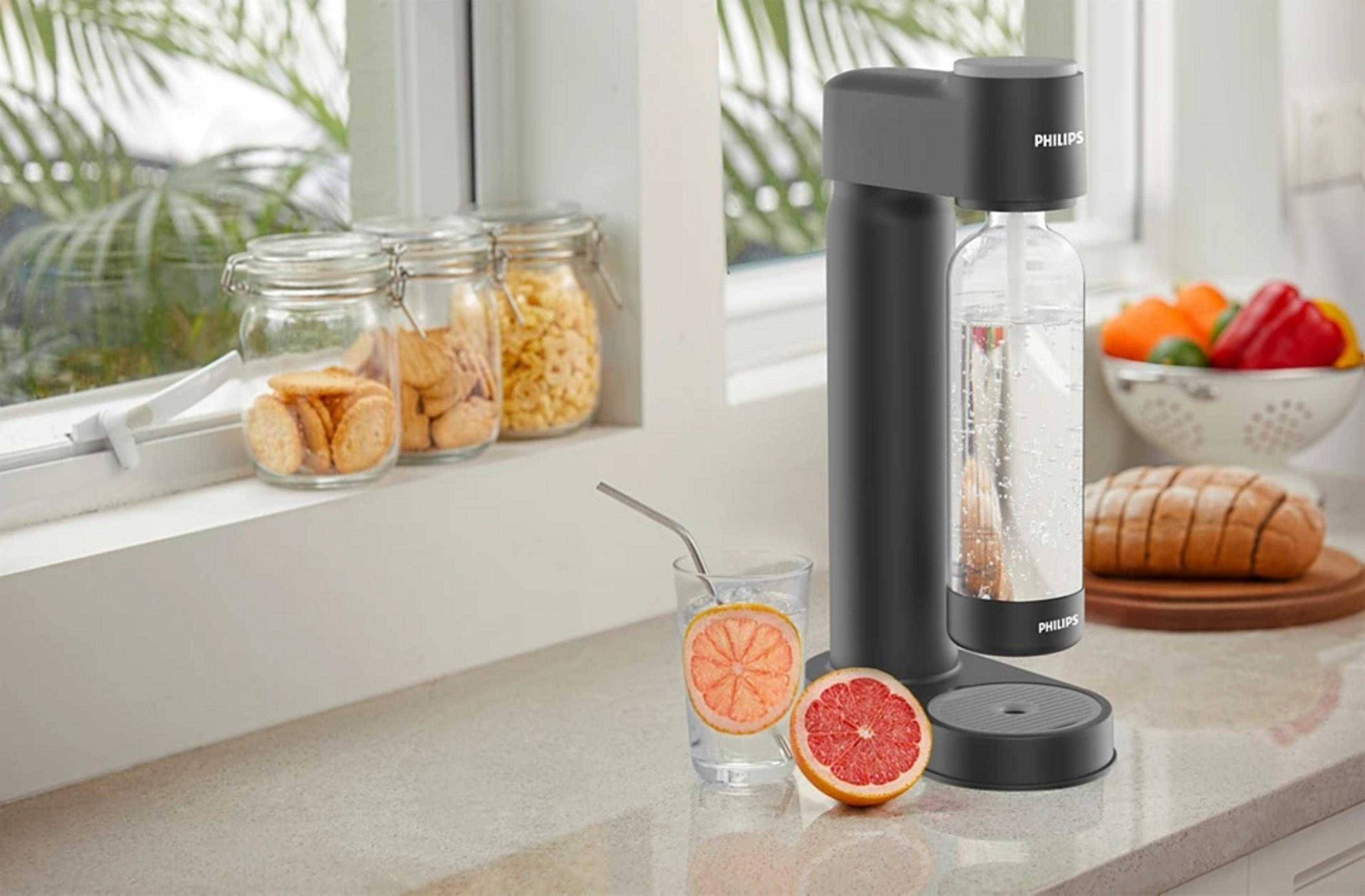 Ein Philips Wassersprudler mit Glas, Grapefruit und Brot auf einer Arbeitsplatte.