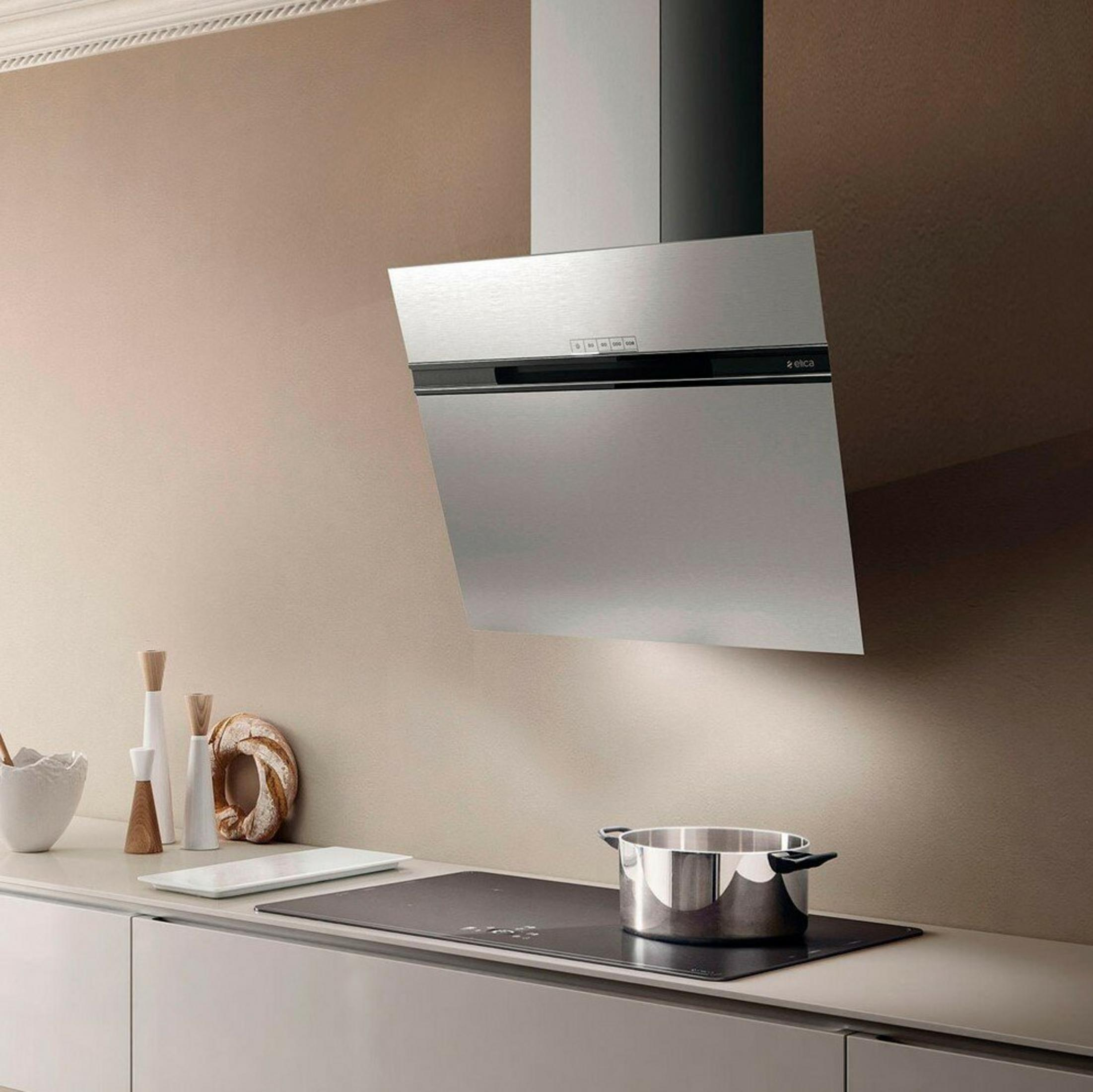 Una cucina moderna con cappa in acciaio inox su piano cottura nero con pentola.