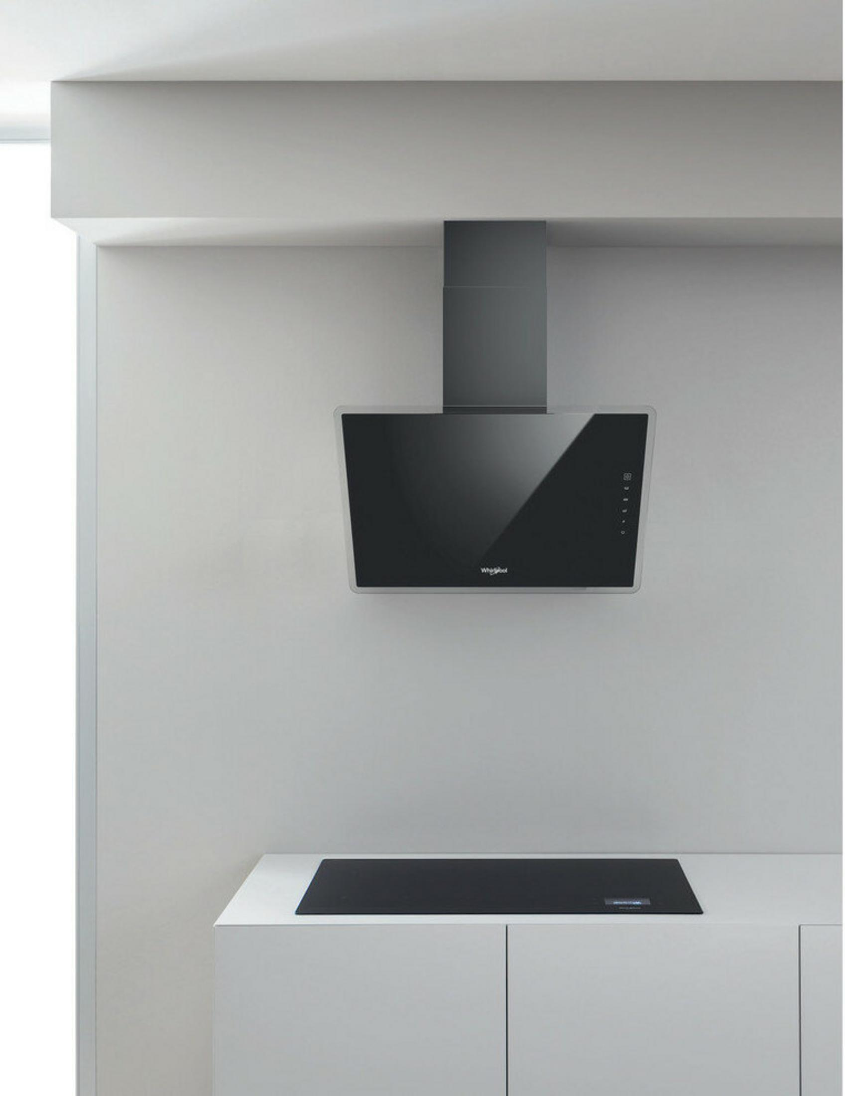 Een moderne keuken met zwarte glaskap boven een zwart inductiefornuis.