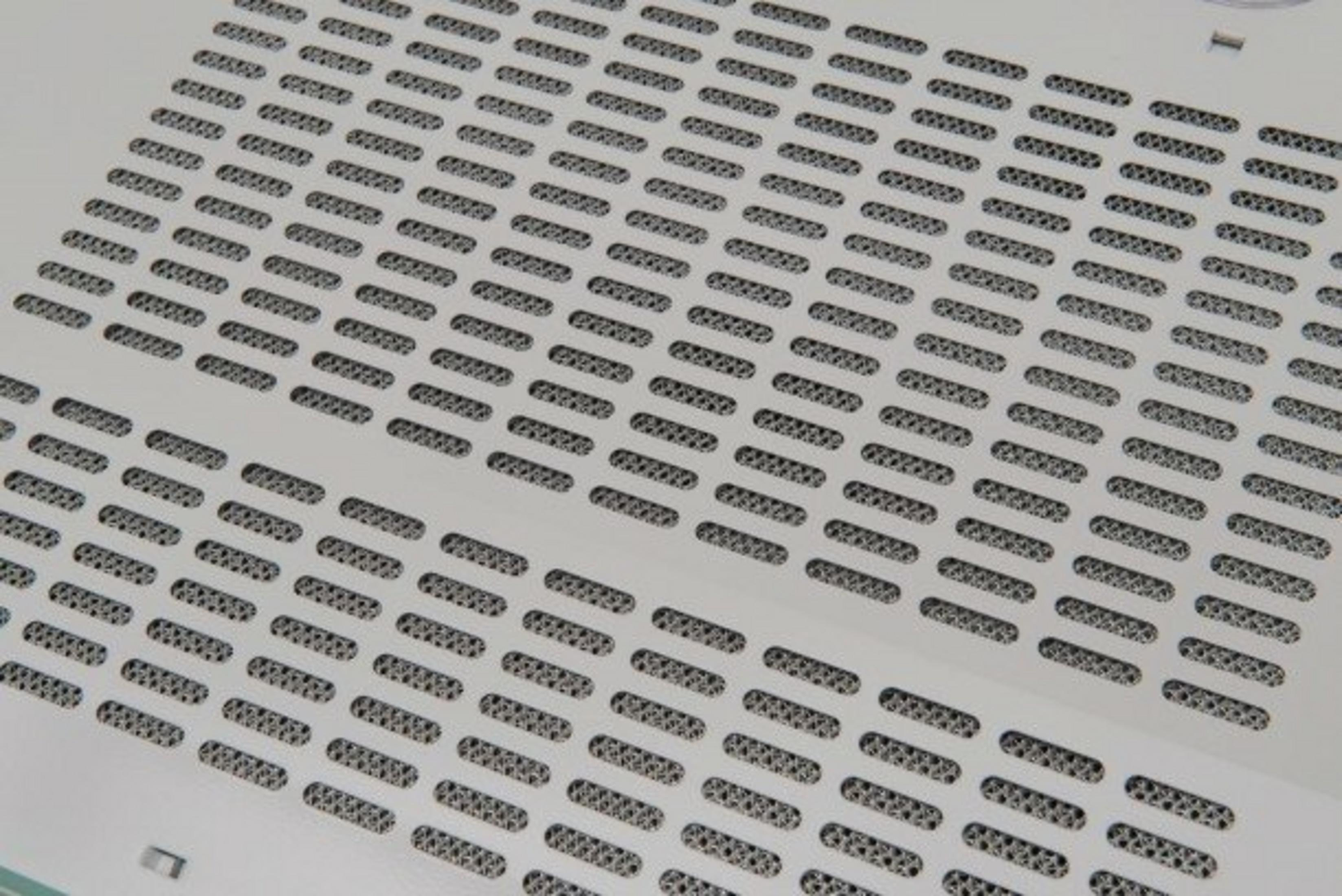 Zbliżenie białej powierzchni z wieloma szczelinowymi otworami wentylacyjnymi.