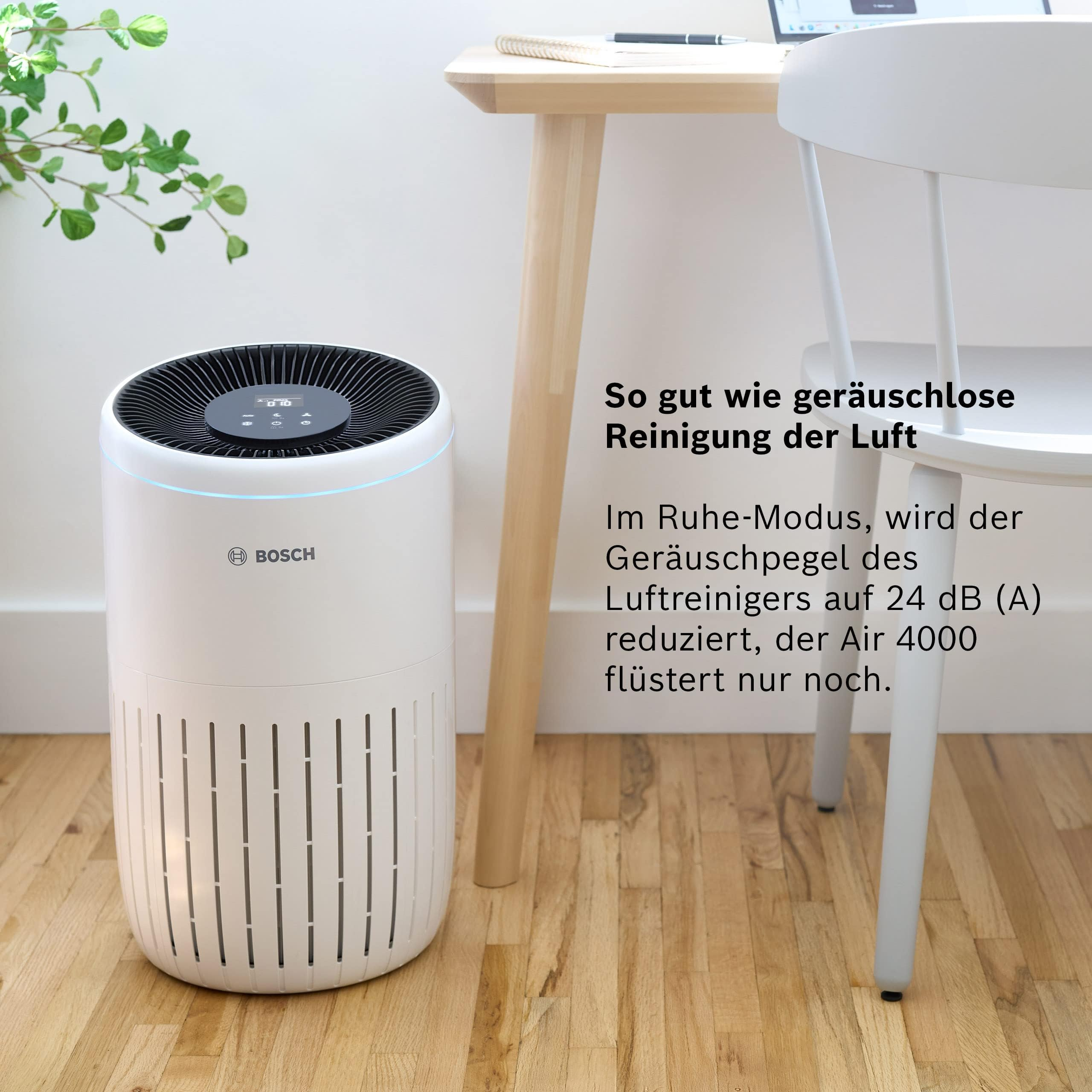 Ein weißer Bosch Luftreiniger steht auf einem Holzboden neben einem Schreibtisch.