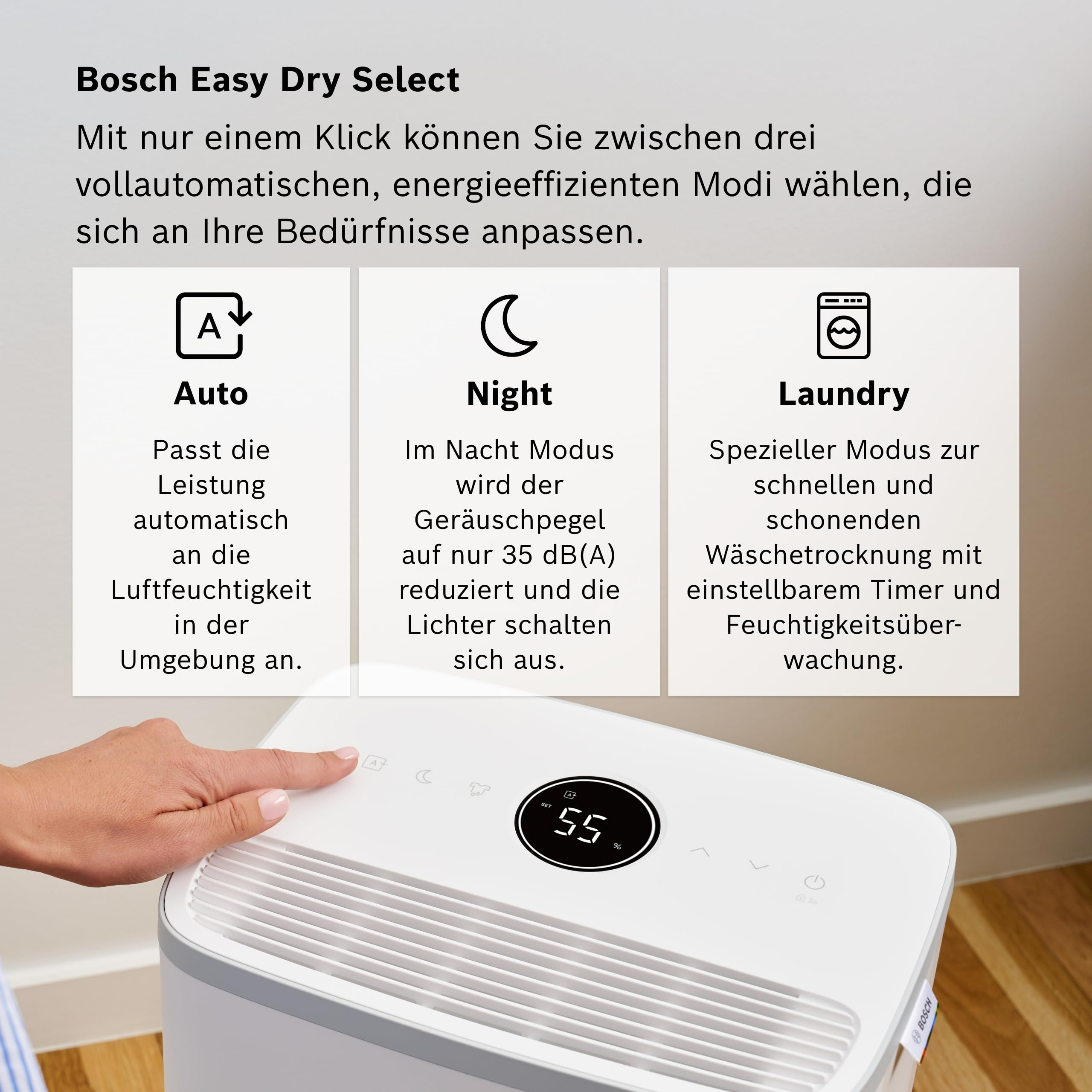 Una mano preme un pulsante su un deumidificatore bianco Bosch con modalità Auto, Notte e Lavanderia.
