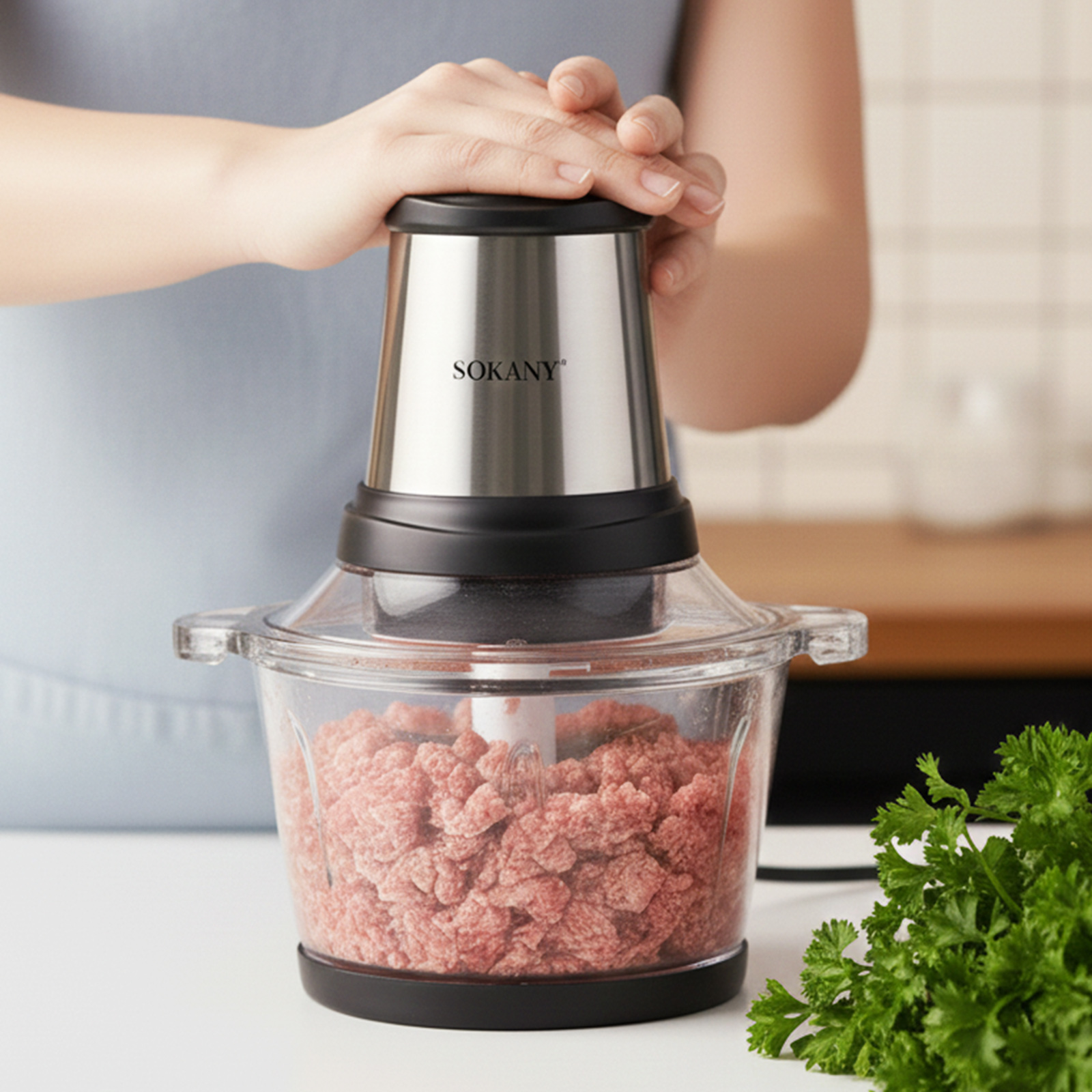 Una persona usa un robot da cucina con carne macinata e prezzemolo.