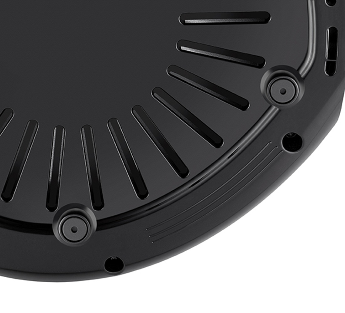 Zbliżenie czarnej teksturowanej powierzchni z promienistymi otworami wentylacyjnymi i dwoma otworami na śruby.