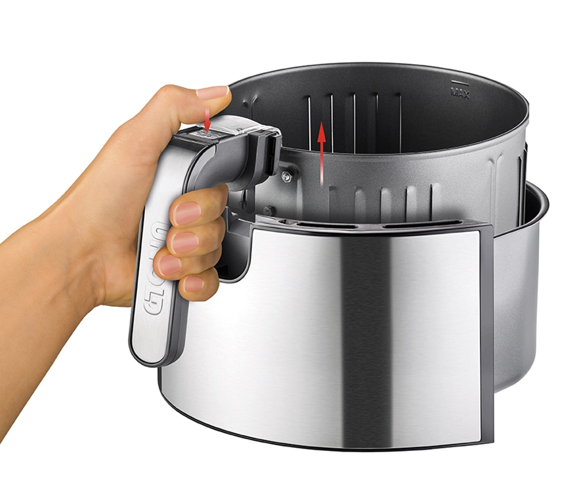 Ręka trzyma uchwyt srebrnego kosza frytkownicy beztłuszczowej.