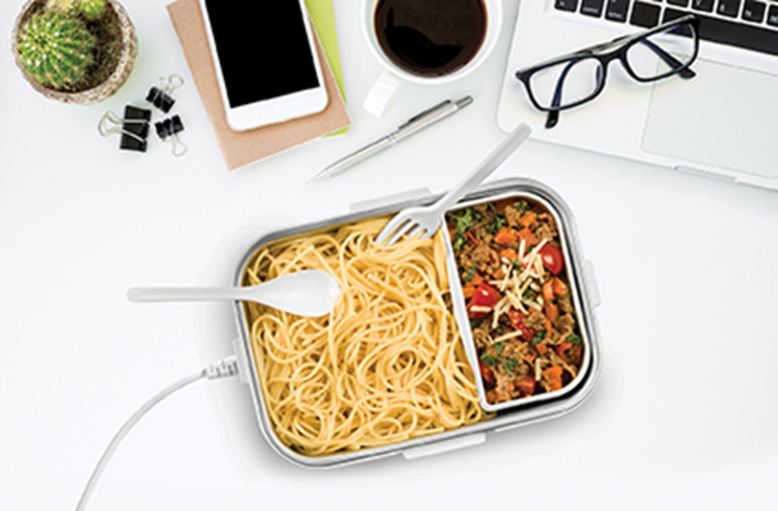 Büroarbeitsplatz mit Lunchbox, Laptop, Kaffee und Handy.