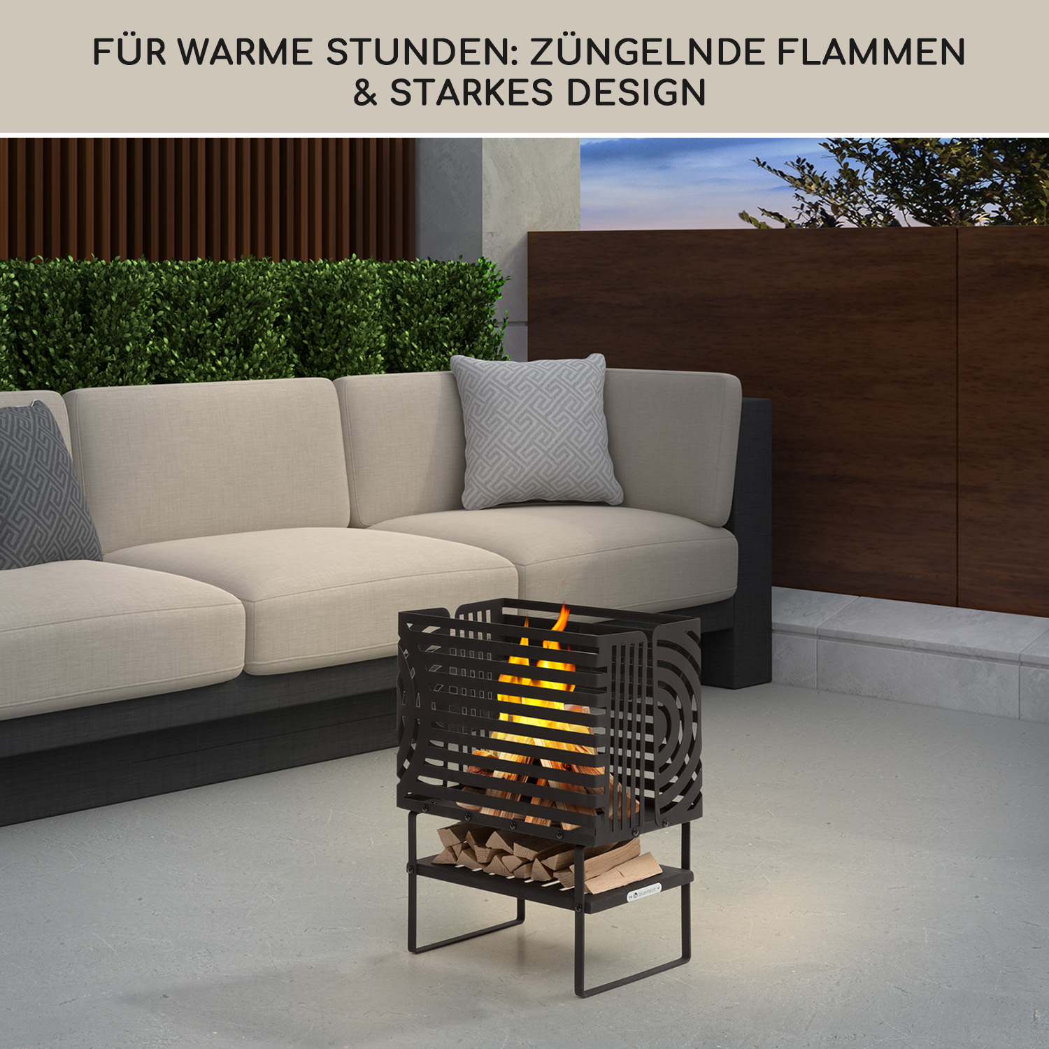 Eine moderne schwarze Feuerstelle mit brennenden Scheiten steht auf einer Terrasse neben einem beigen Sofa.