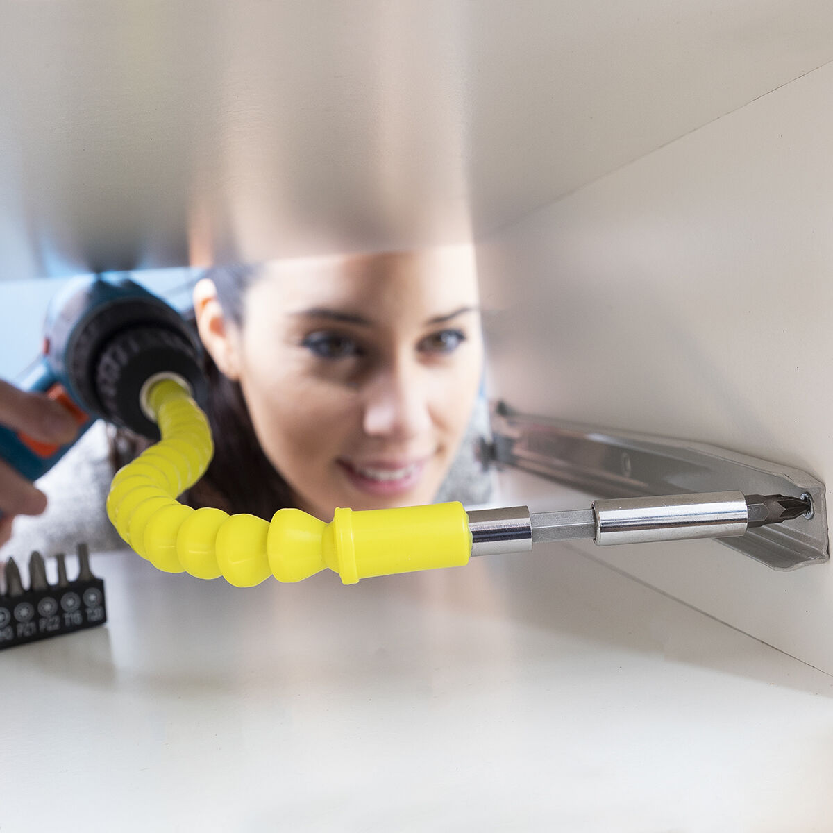 Donna usa un porta inserti flessibile giallo con trapano per fissare una guida per cassetti.