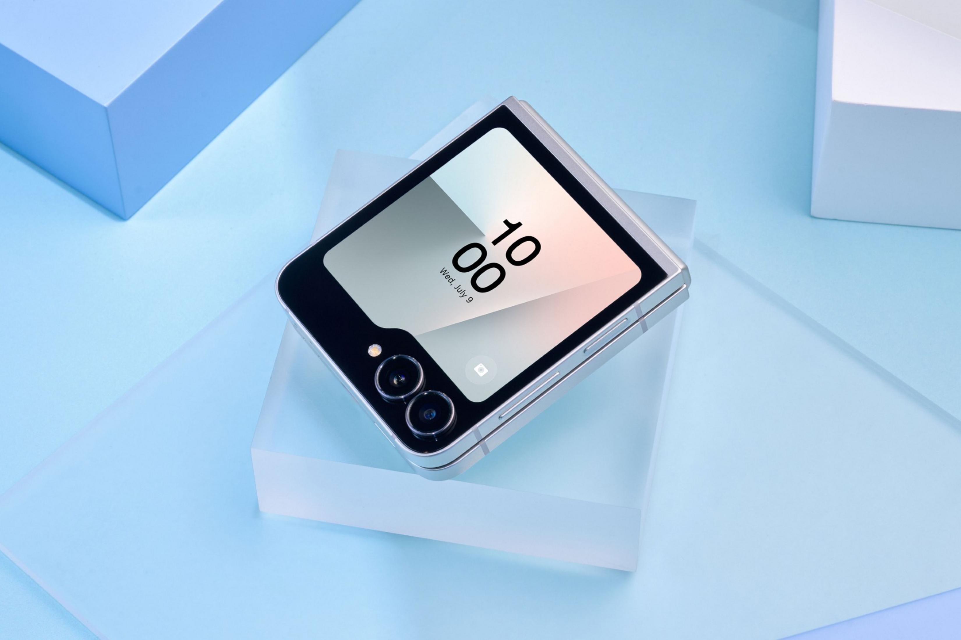 Srebrny telefon składany z dwoma aparatami na niebieskim tle.