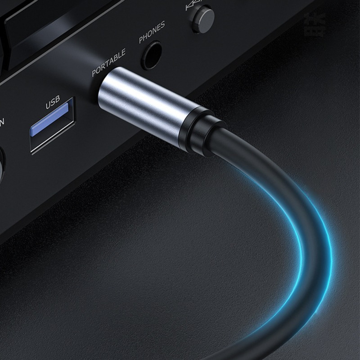 Ein silbernes Kabel wird in ein schwarzes Gerät mit USB- und PHONES-Anschlüssen gesteckt.