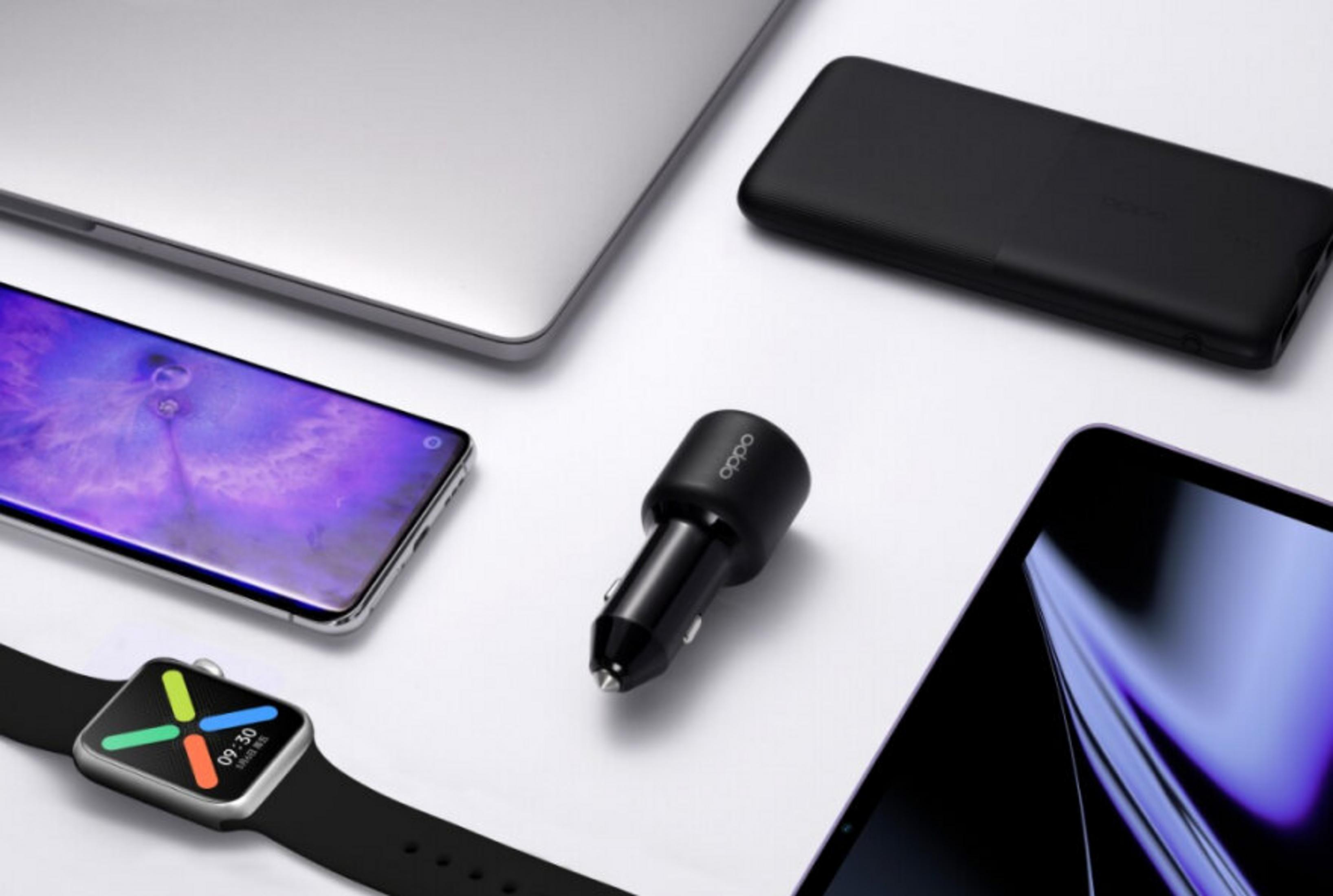 Zilveren laptop, zwarte powerbank, autolader, smartphone en smartwatch op een witte ondergrond.