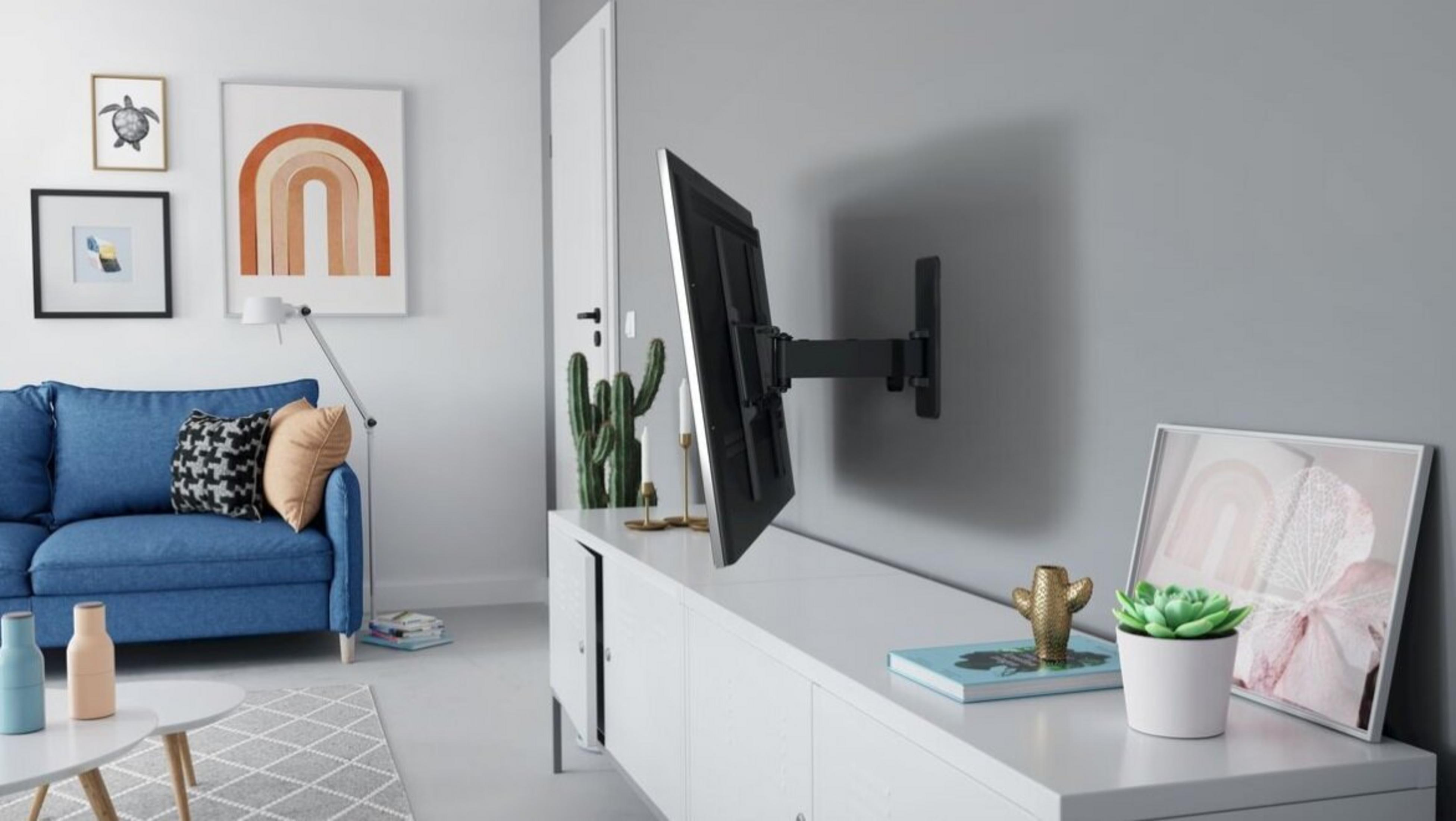 Nowoczesny salon z niebieską sofą, białym kredensem i uchwytem ściennym TV.