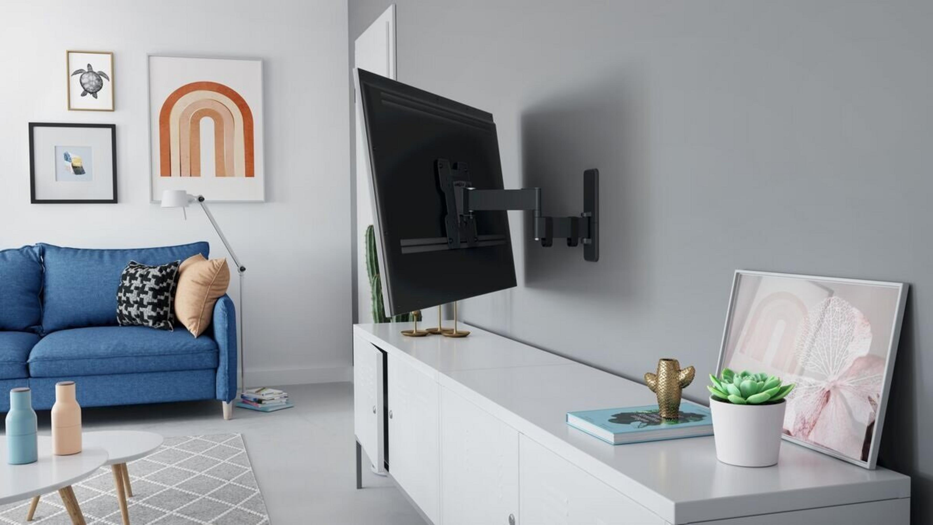 Una sala de estar moderna con sofá azul, mueble de TV blanco, televisión y arte en la pared.