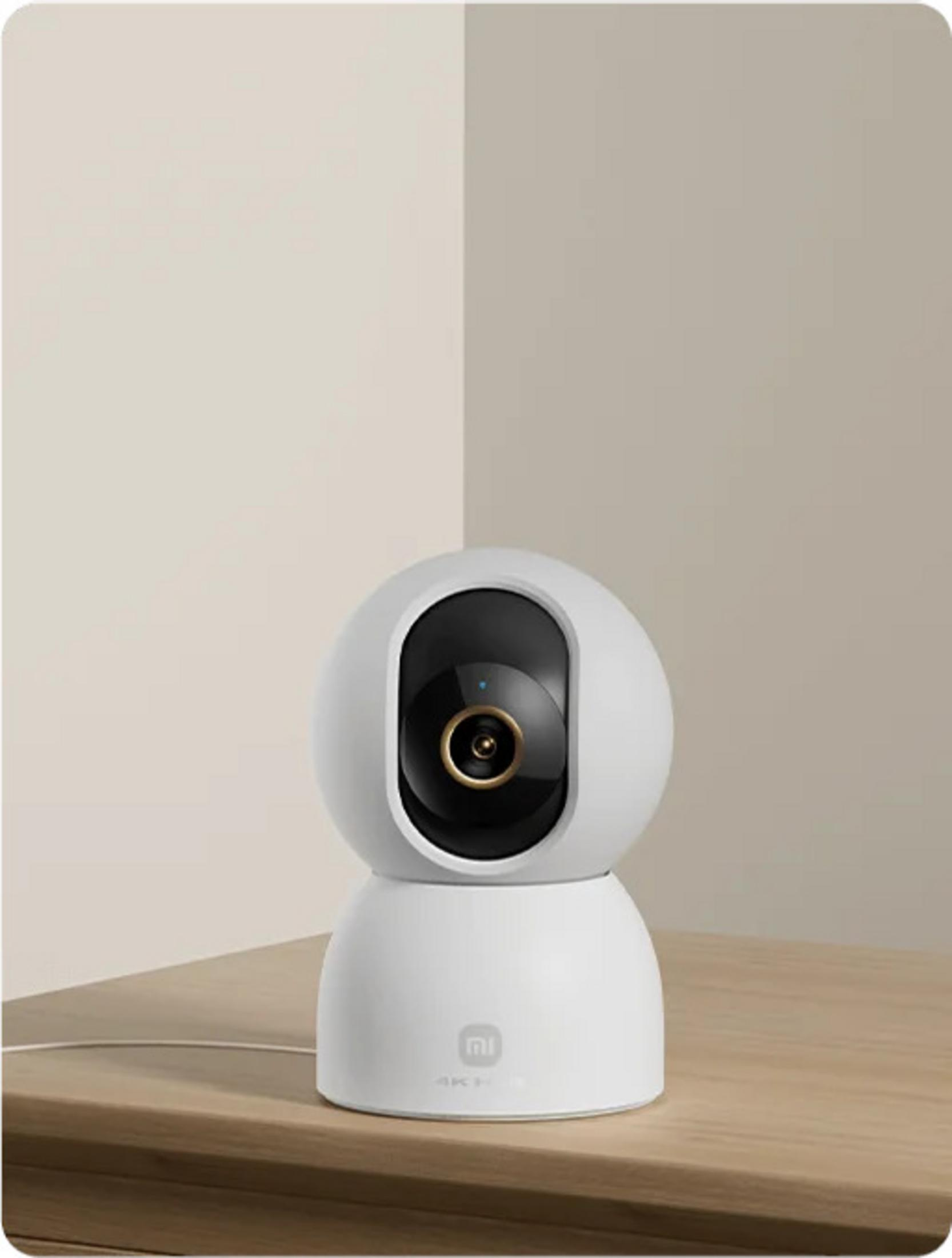 Biała kamera bezpieczeństwa z obrotem i pochyleniem, czarna soczewka, na drewnianym stole.